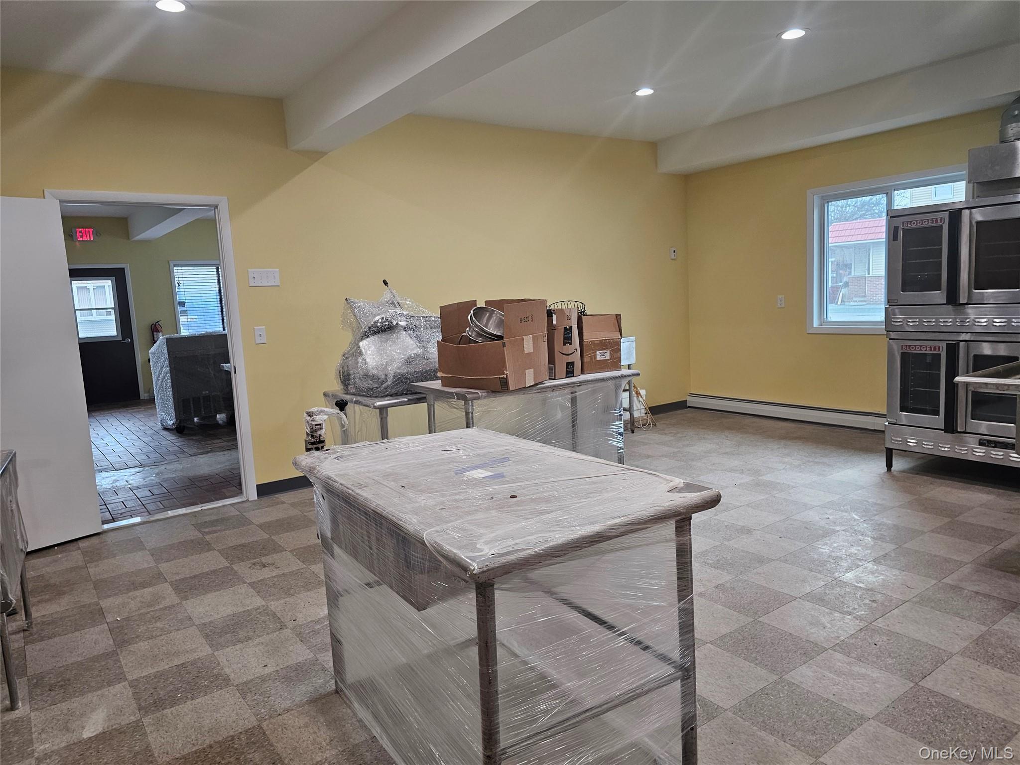 Kitchen featuring plenty of natural light, beamed ceiling, recessed lighting, light flooring, and a baseboard radiator