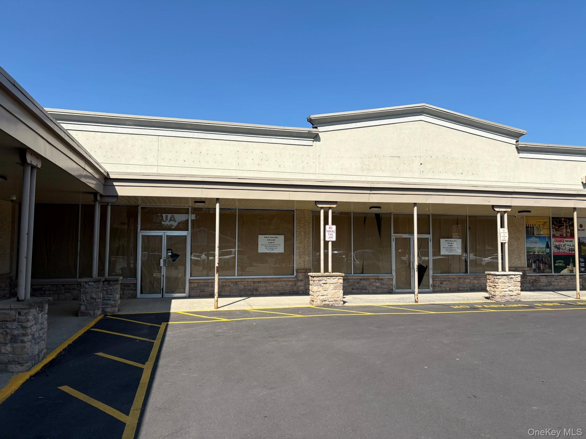 View of exterior entry with stone siding and uncovered parking