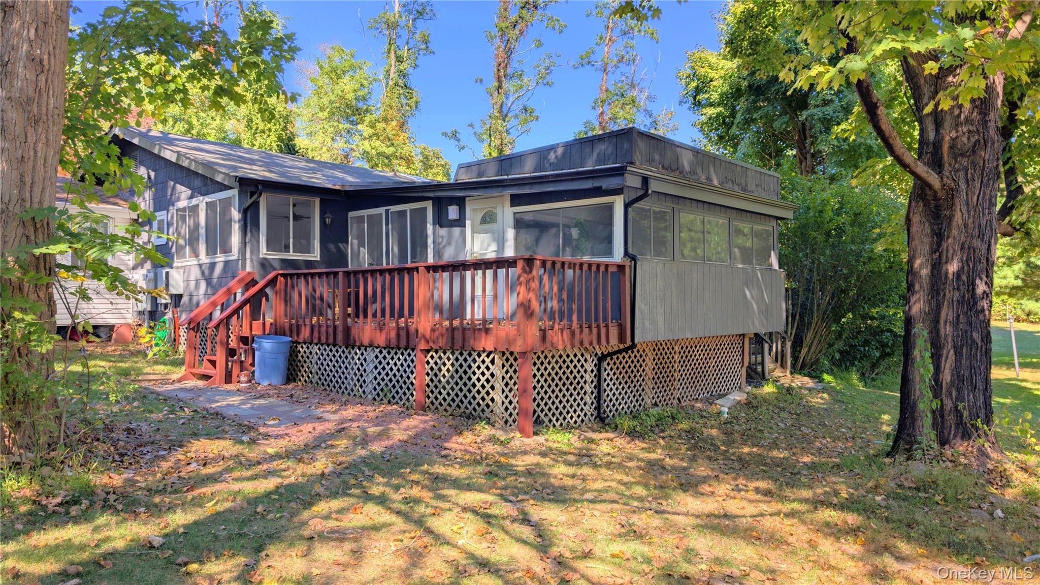 Rear view of house featuring a sunroom and a wooden deck