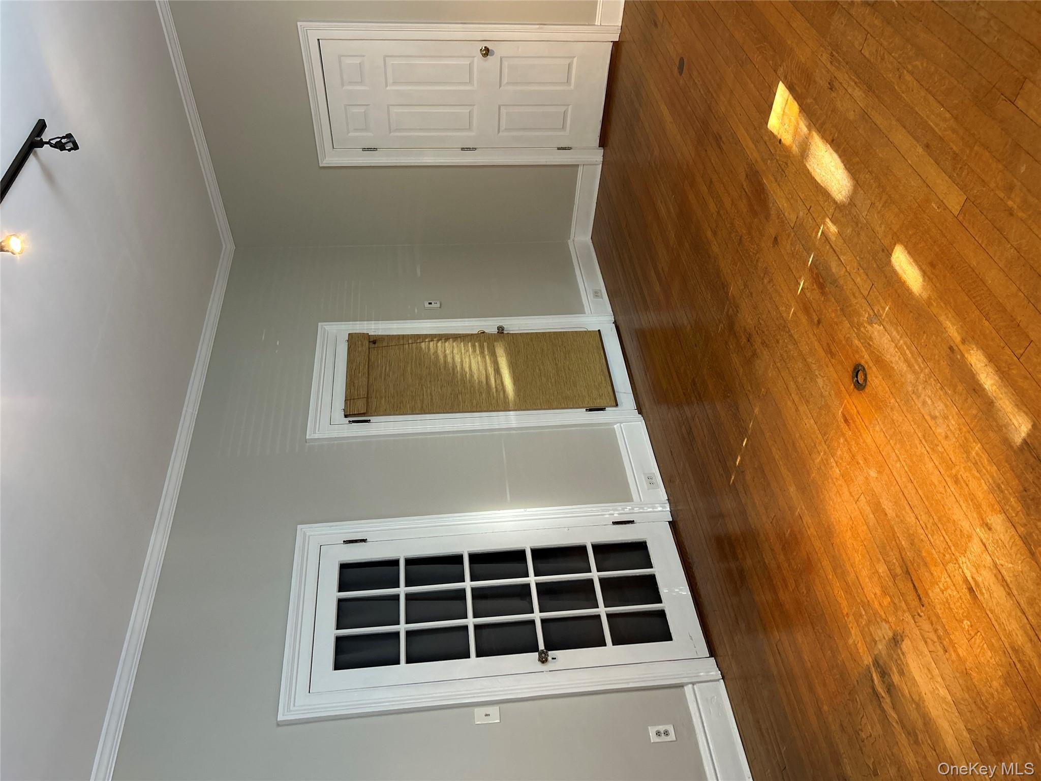 Empty room featuring dark wood-style flooring, crown molding, and track lighting