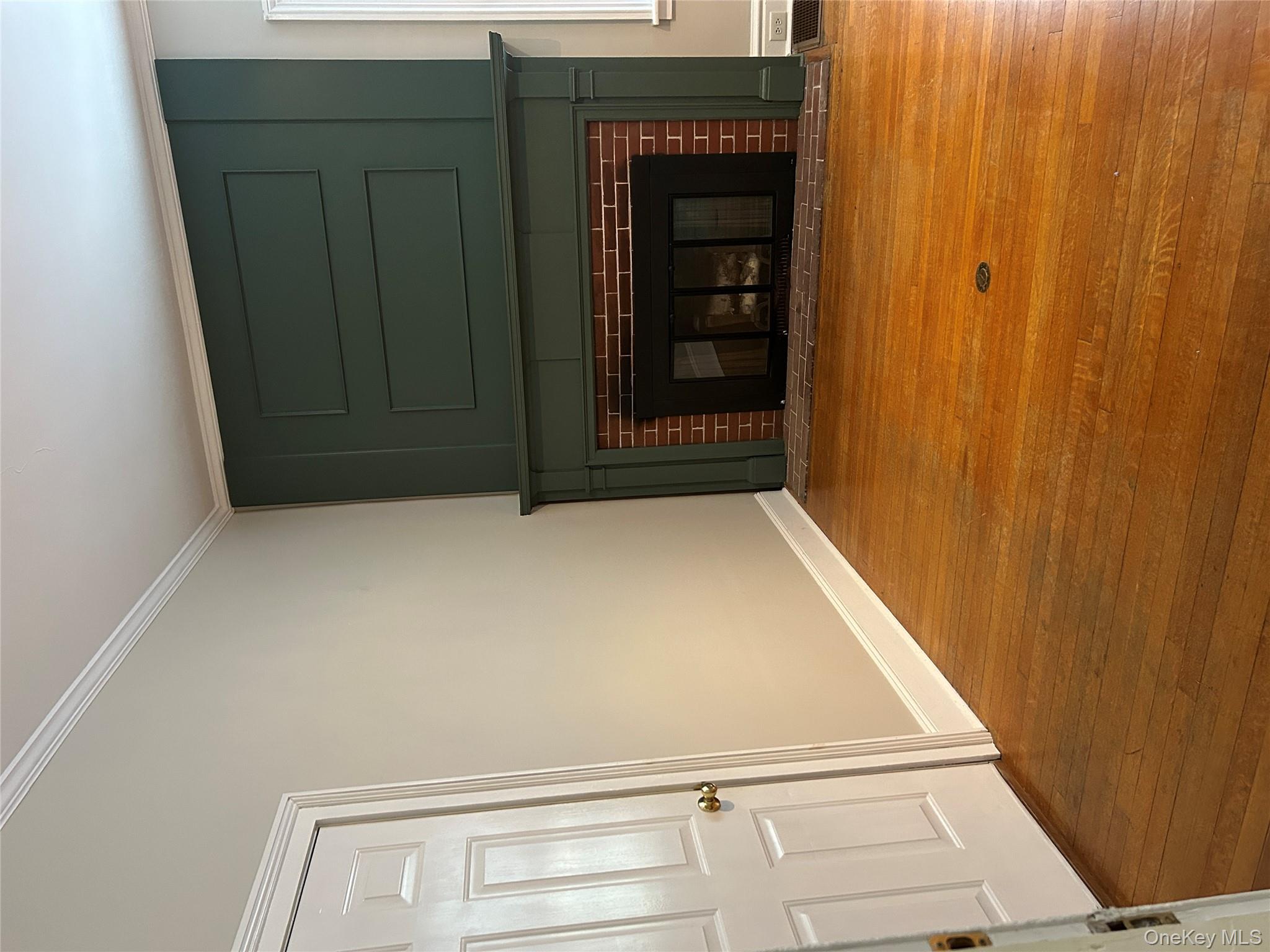 Unfurnished living room featuring a fireplace with flush hearth, ornamental molding, and hardwood / wood-style floors