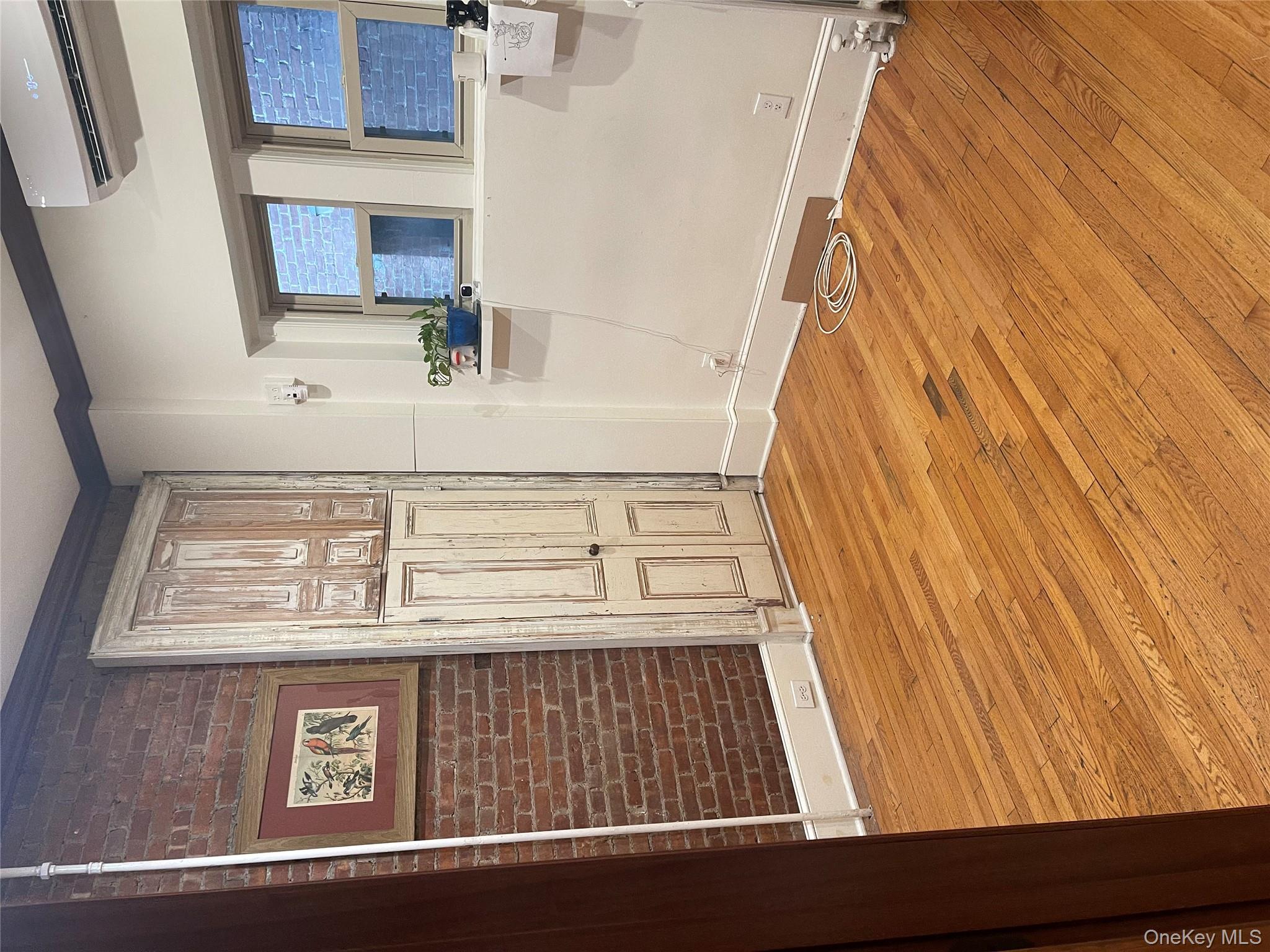 Spare room featuring light wood-style floors, brick wall, and a wall mounted AC