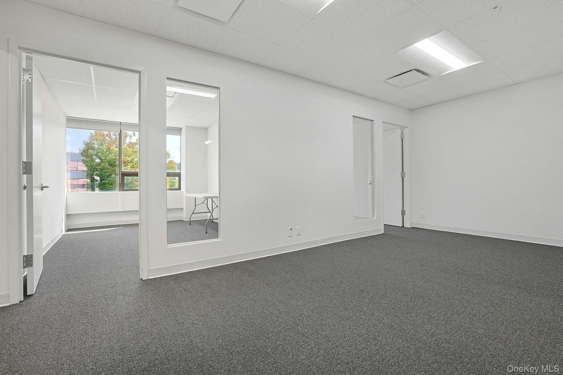 Empty room with a paneled ceiling and dark carpet