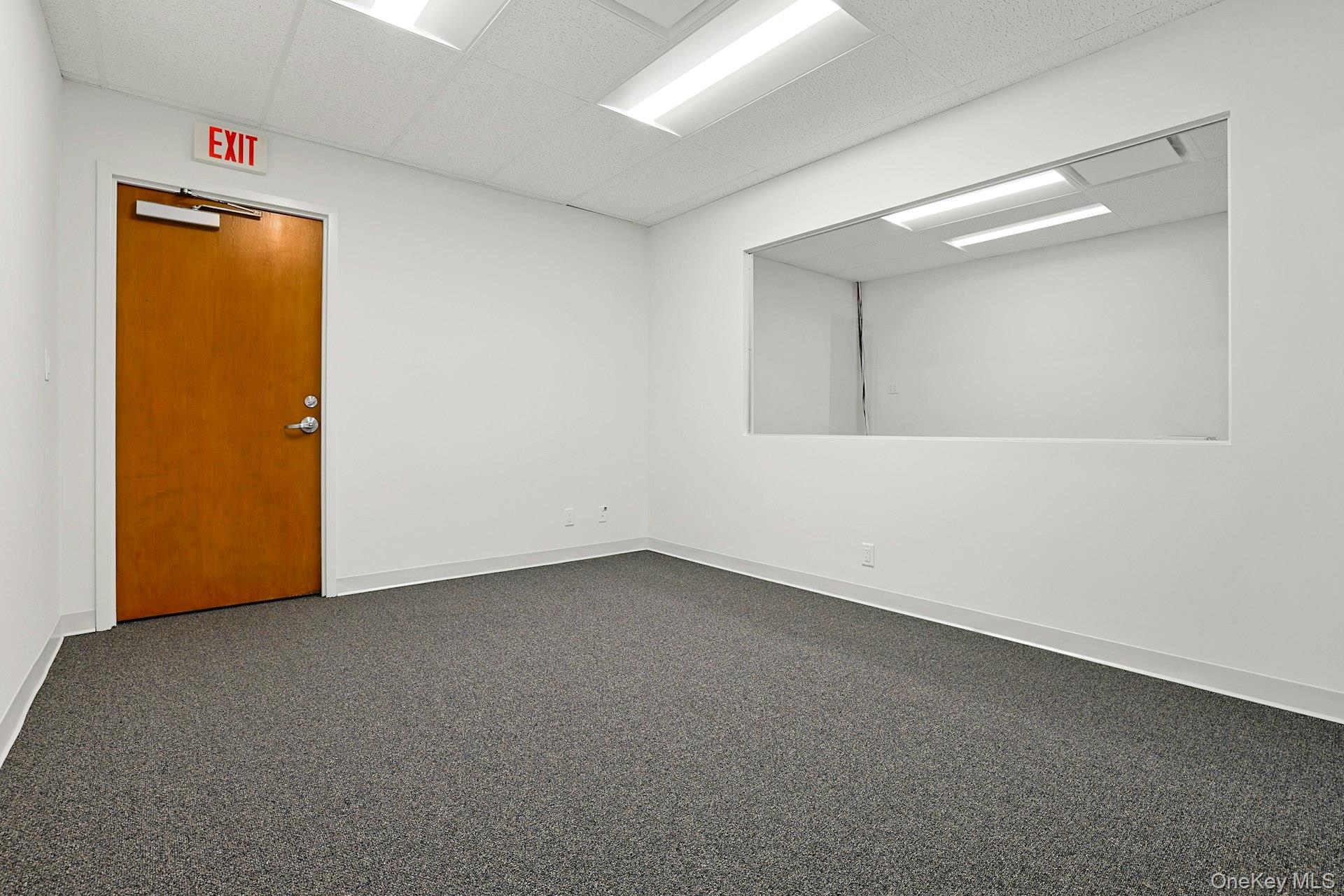 Empty room featuring a paneled ceiling and baseboards