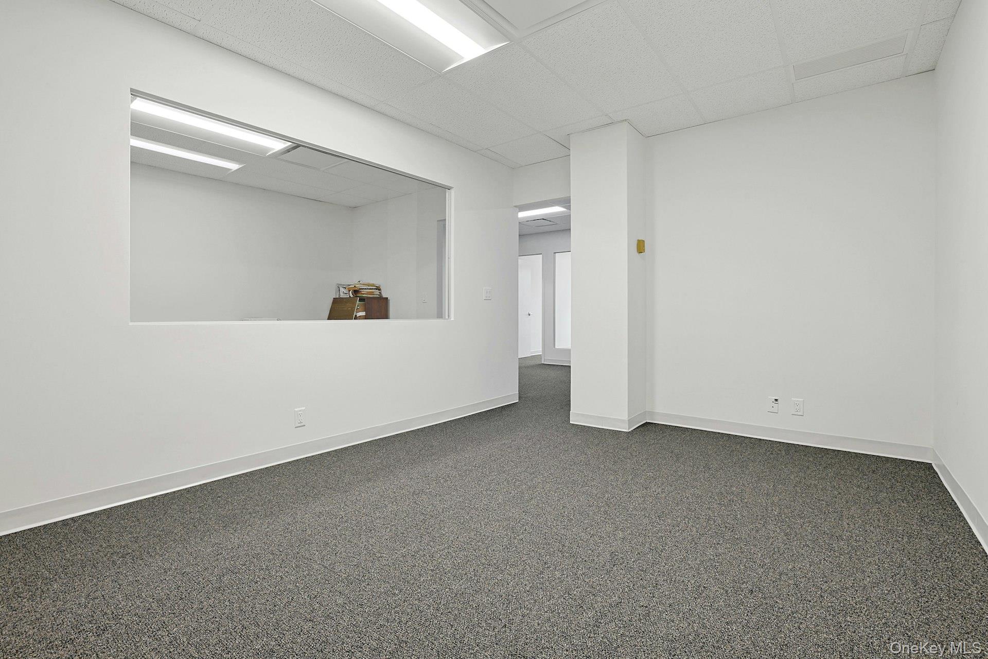 Carpeted empty room featuring baseboards and a paneled ceiling