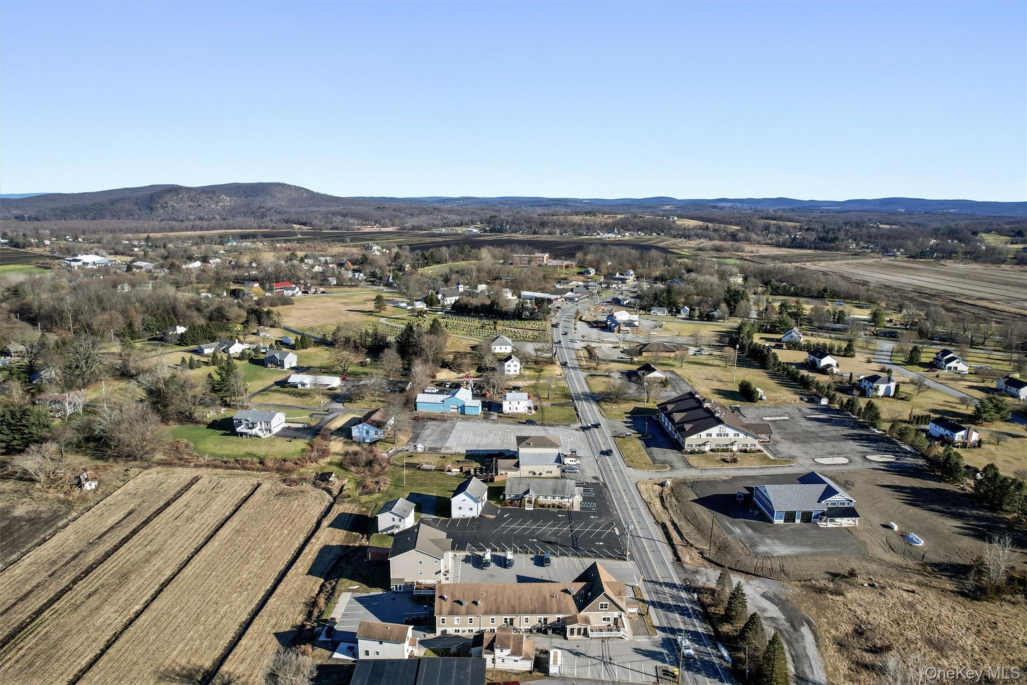 Aerial view of property and surrounding area featuring a mountain backdrop
