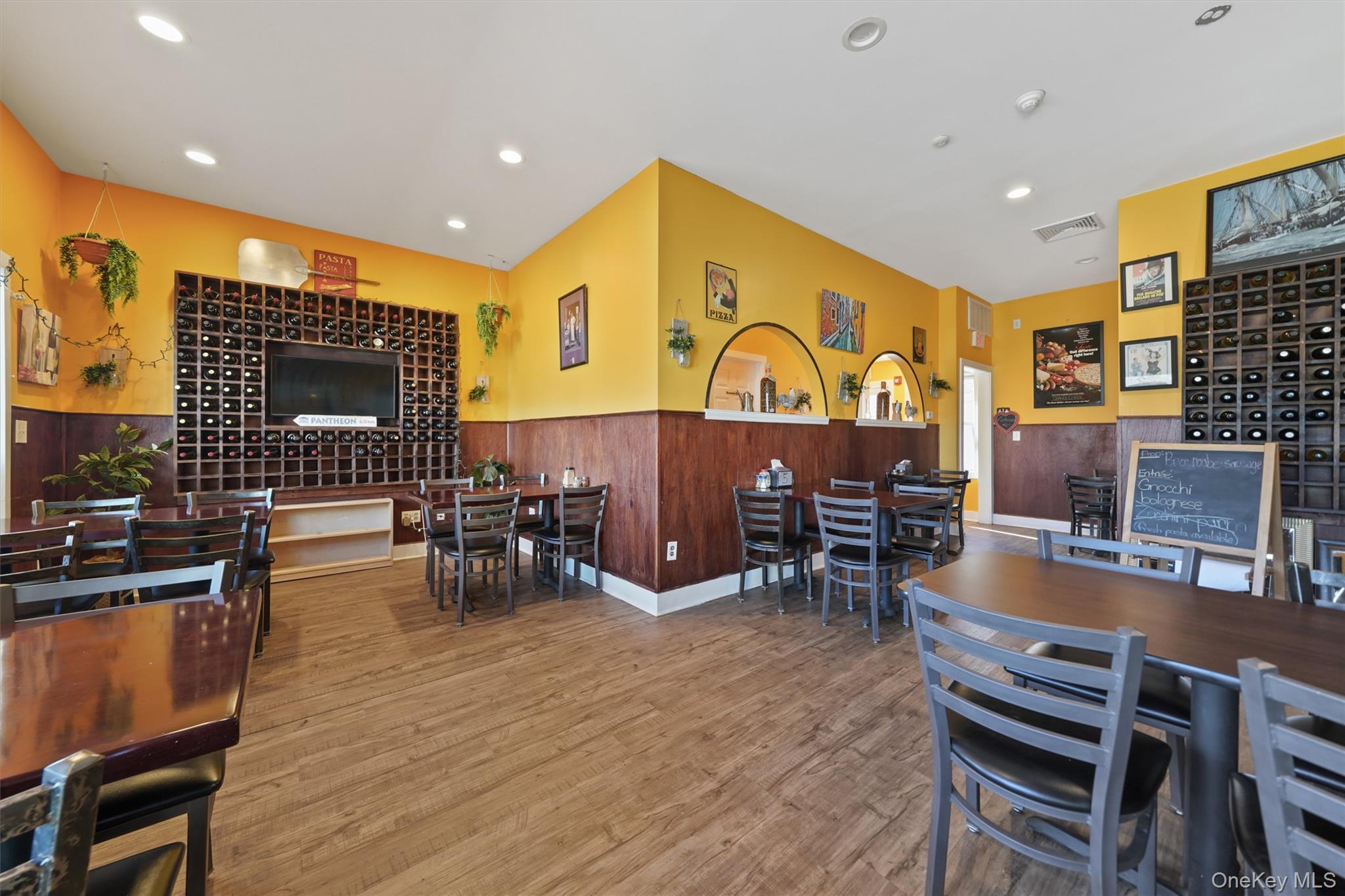 Dining space with light wood-type flooring, a wainscoted wall, recessed lighting, and wooden walls