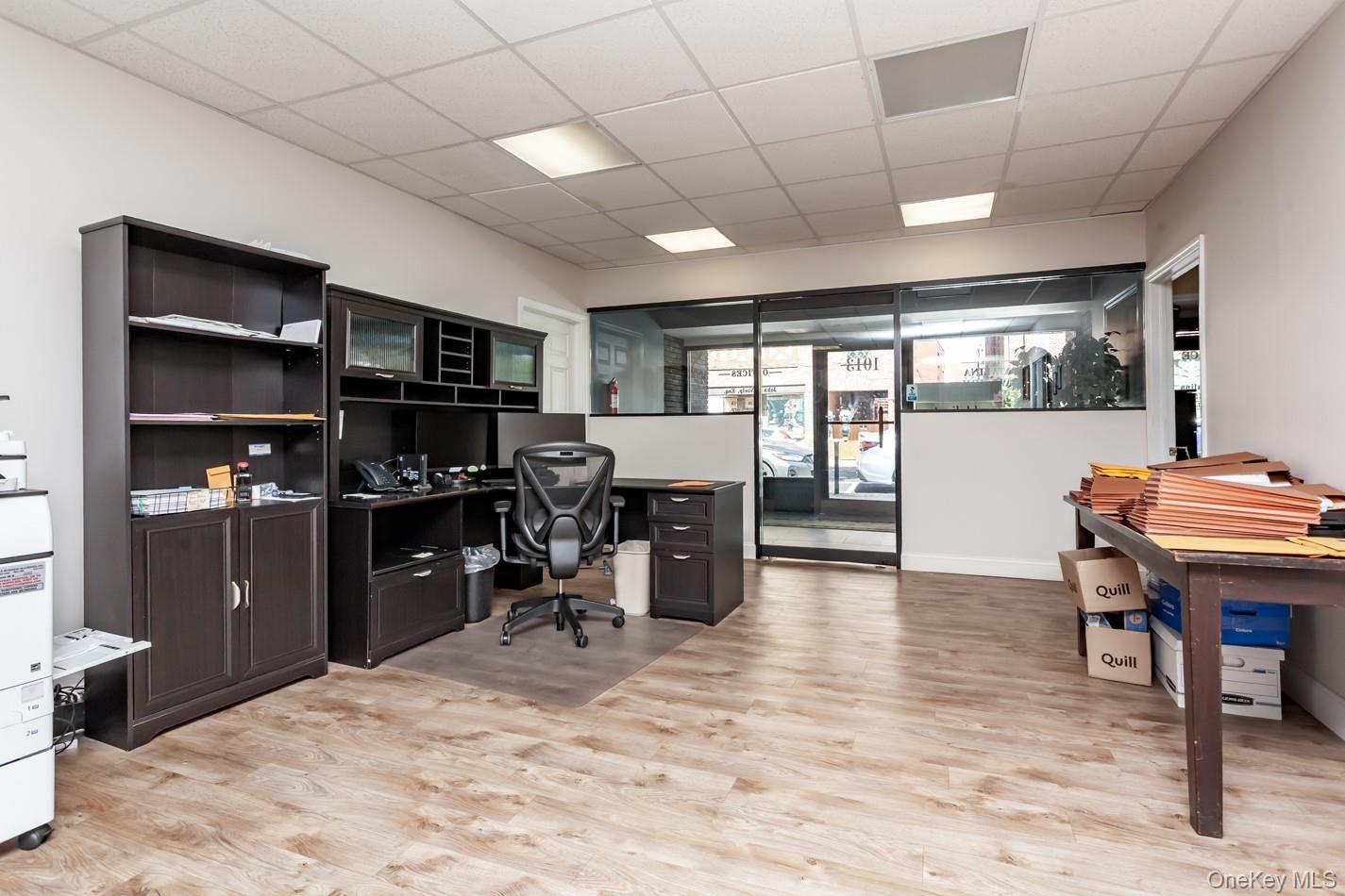 Office featuring a paneled ceiling, light wood-type flooring, and built in desk