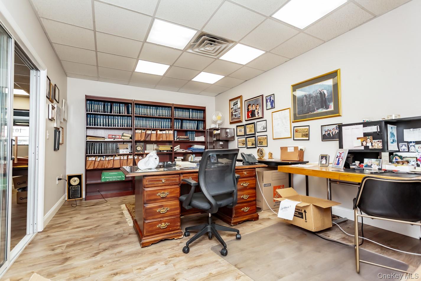 Office space with a drop ceiling, light wood-type flooring, and built in desk