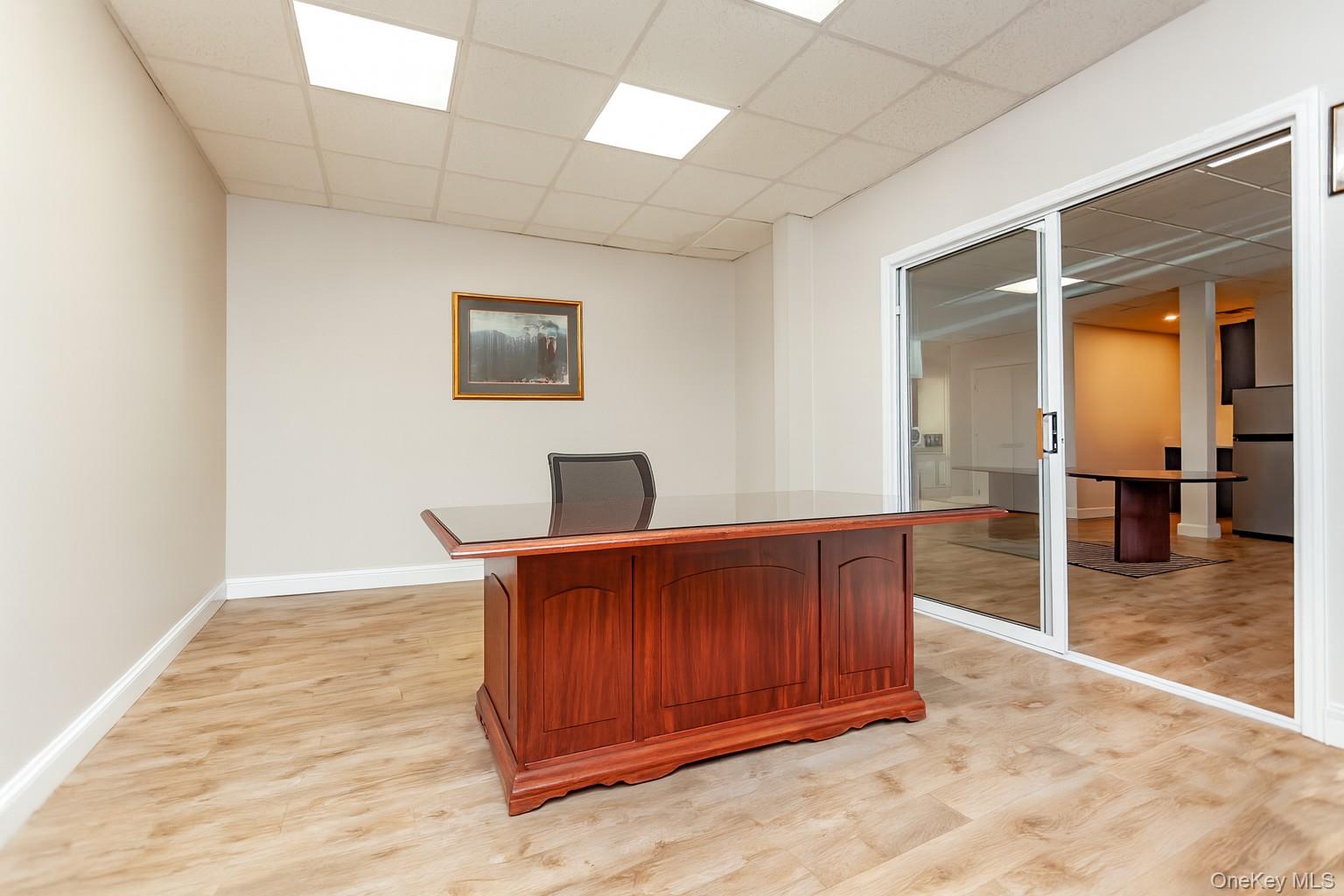 (Digitally Decluttered) Unfurnished office featuring a drop ceiling and light wood finished floors