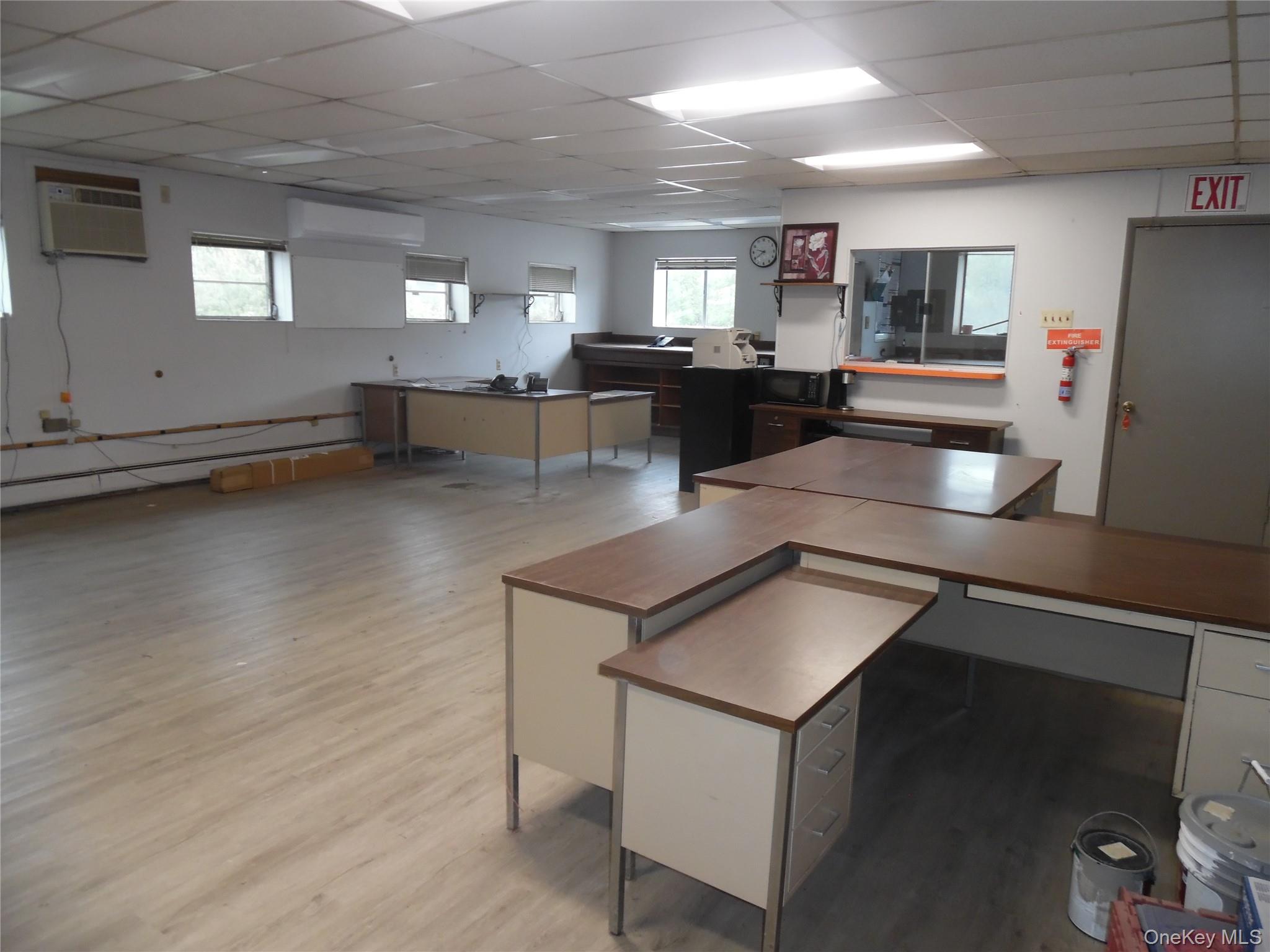 Office featuring a drop ceiling, plenty of natural light, light wood-style flooring, an AC wall unit, and a wall mounted AC