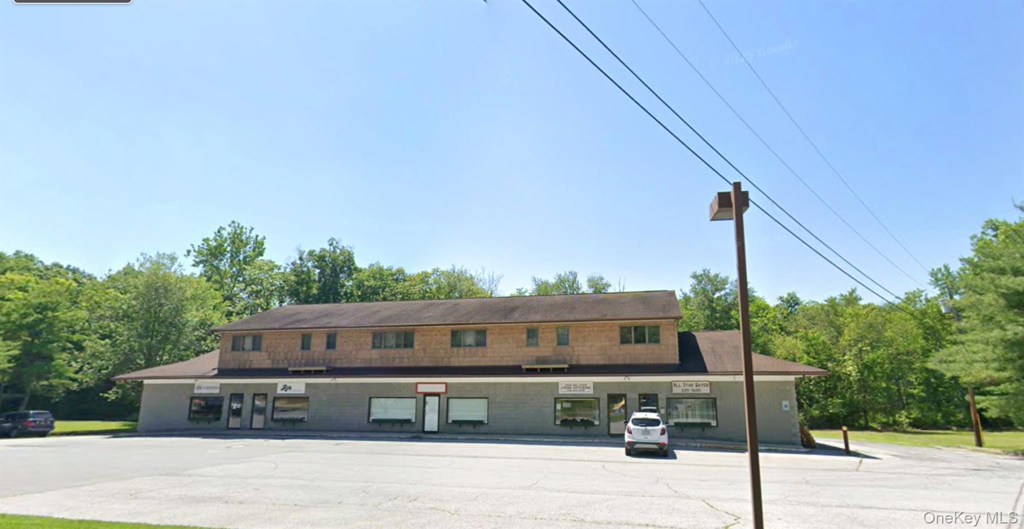 View of property with uncovered parking and view of wooded area