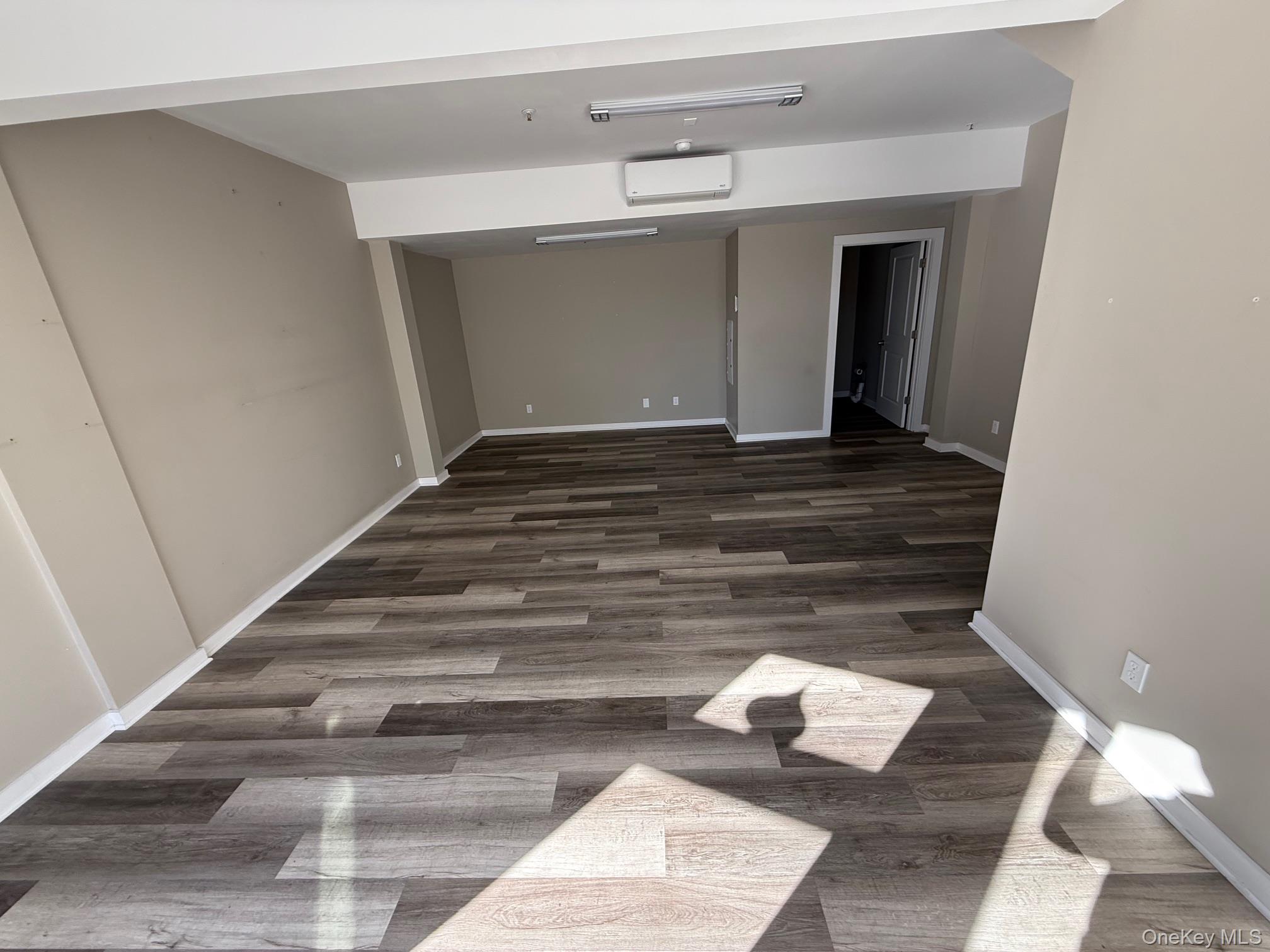 Empty room featuring dark wood finished floors and a wall mounted AC
