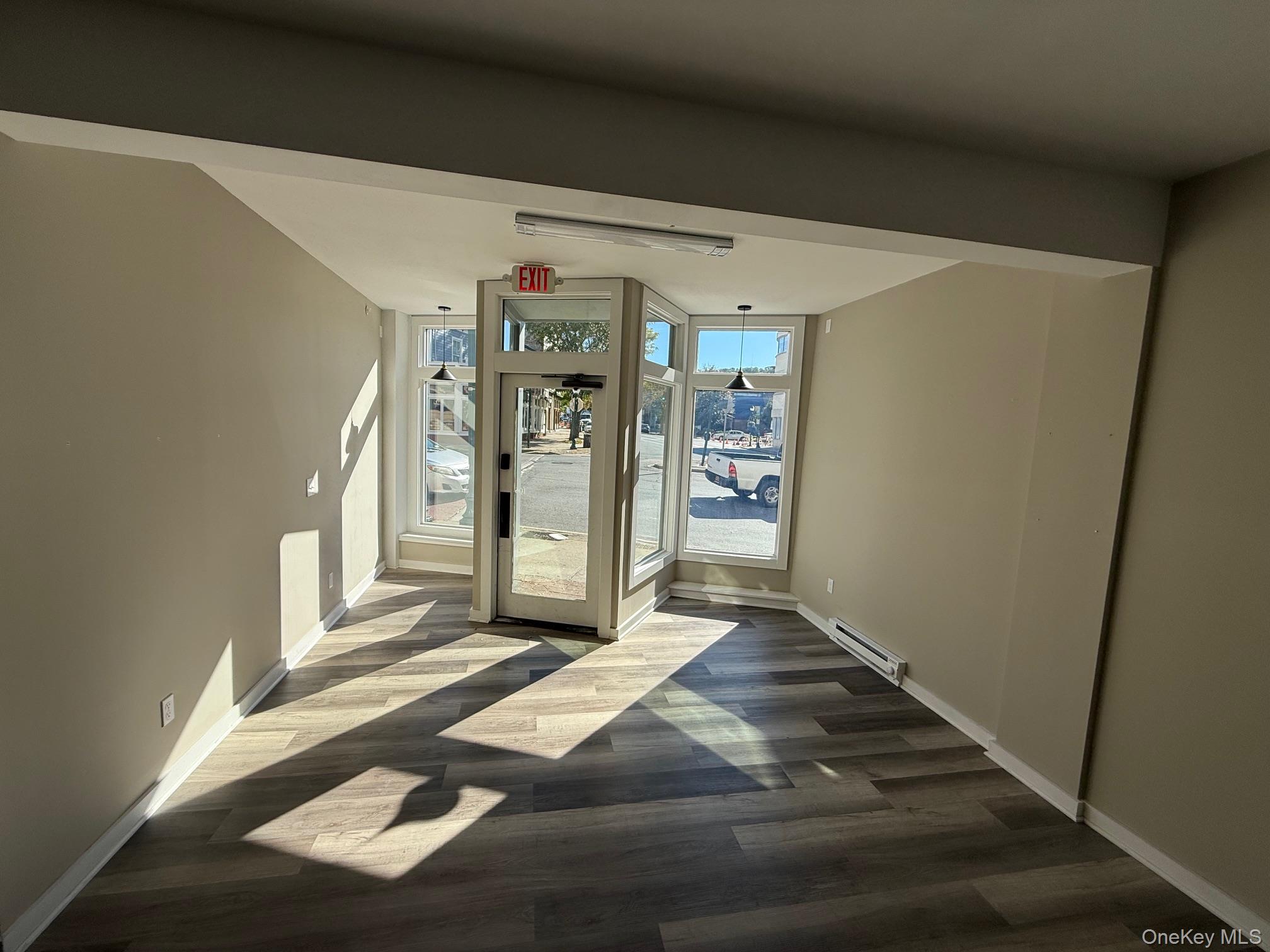 Doorway with wood finished floors and baseboard heating