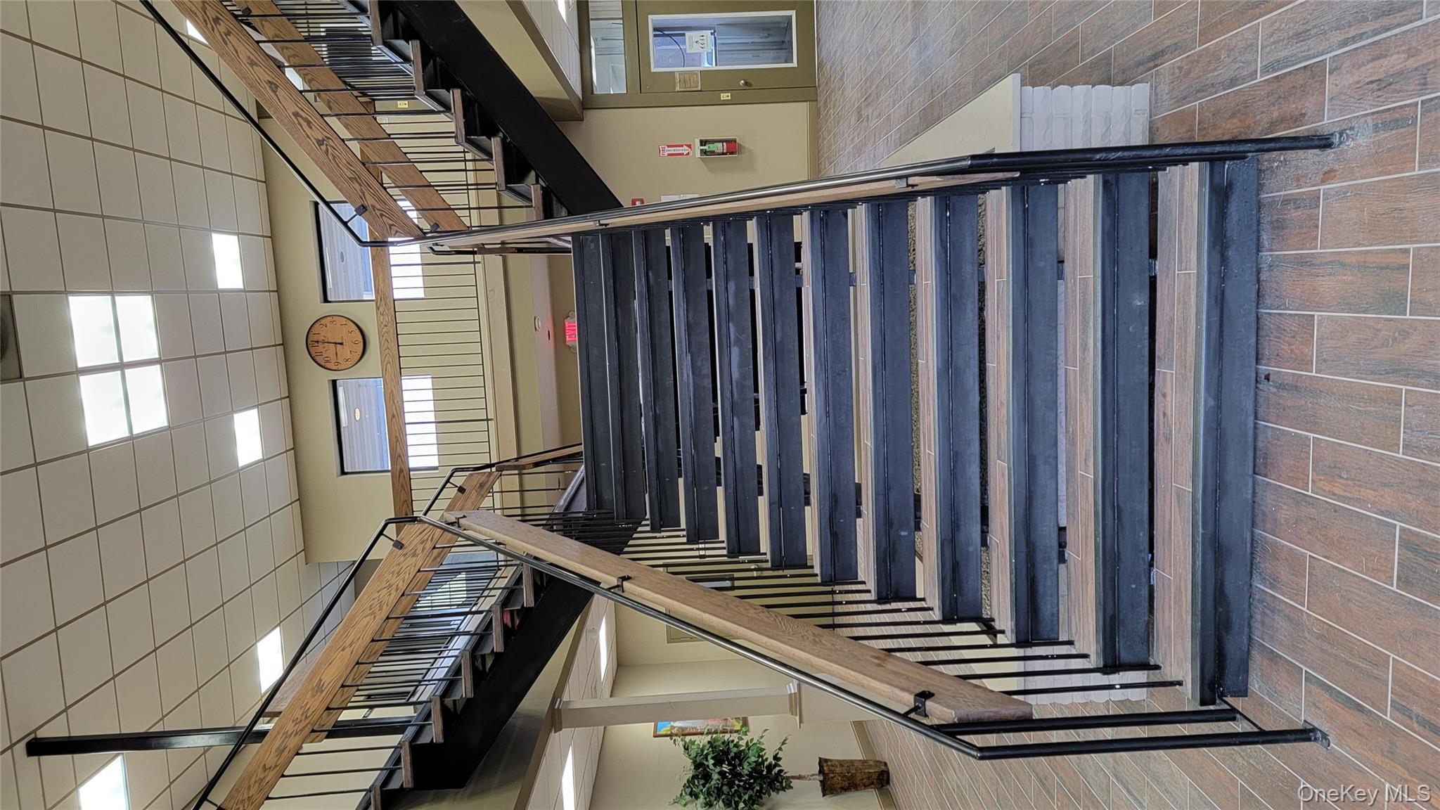 Stairway featuring a high ceiling, a paneled ceiling, and wood finish floors