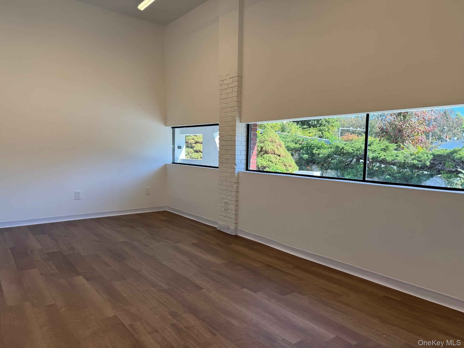 Spare room featuring dark wood-style floors and baseboards