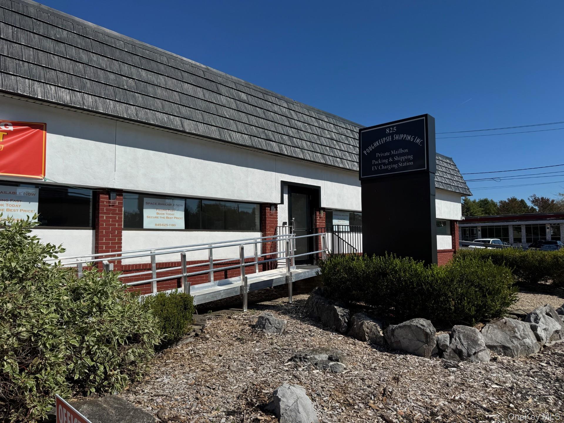 View of side of property featuring mansard roof, stucco siding, and brick siding