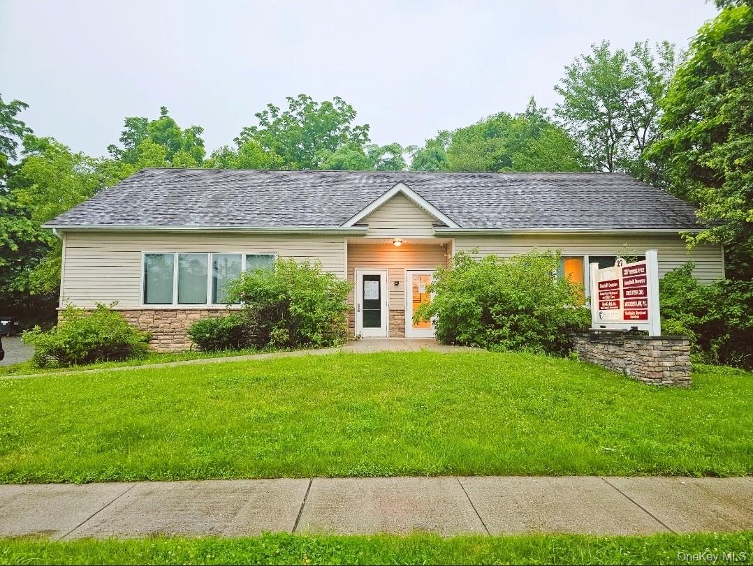 Ranch-style house featuring a front yard, stone siding, and roof with shingles