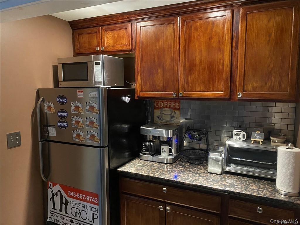 Kitchen featuring decorative backsplash, stainless steel appliances, and dark stone counters