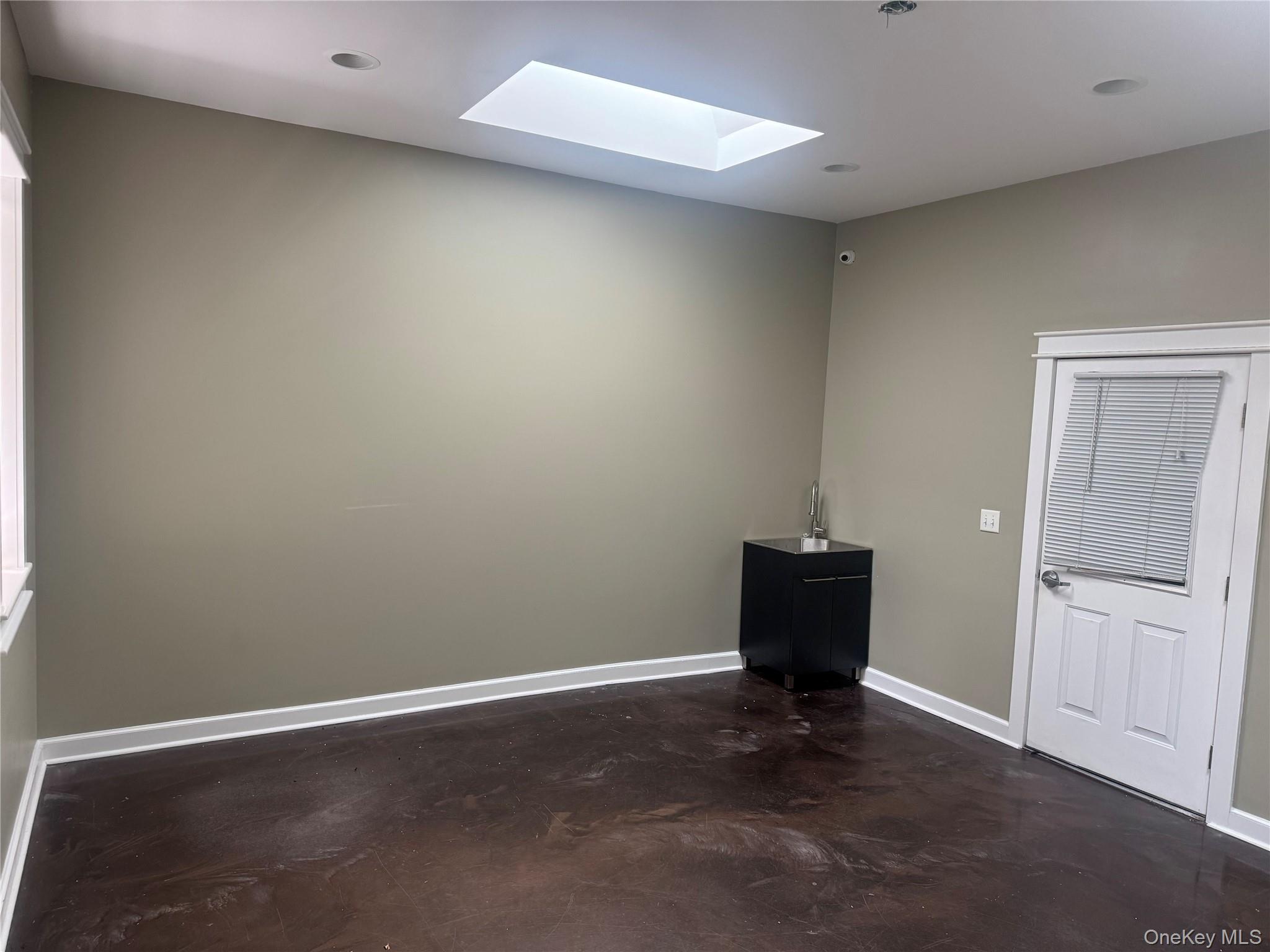 Empty room featuring a skylight, concrete floors, and recessed lighting