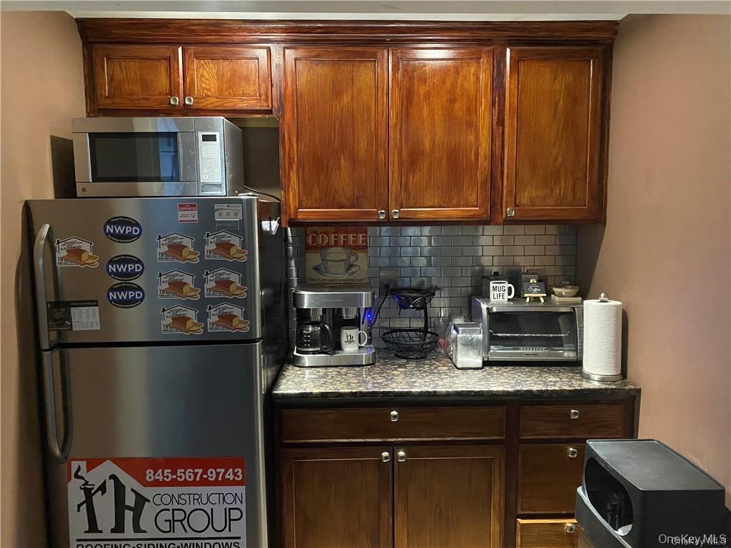 Kitchen with stainless steel appliances, tasteful backsplash, and dark stone counters