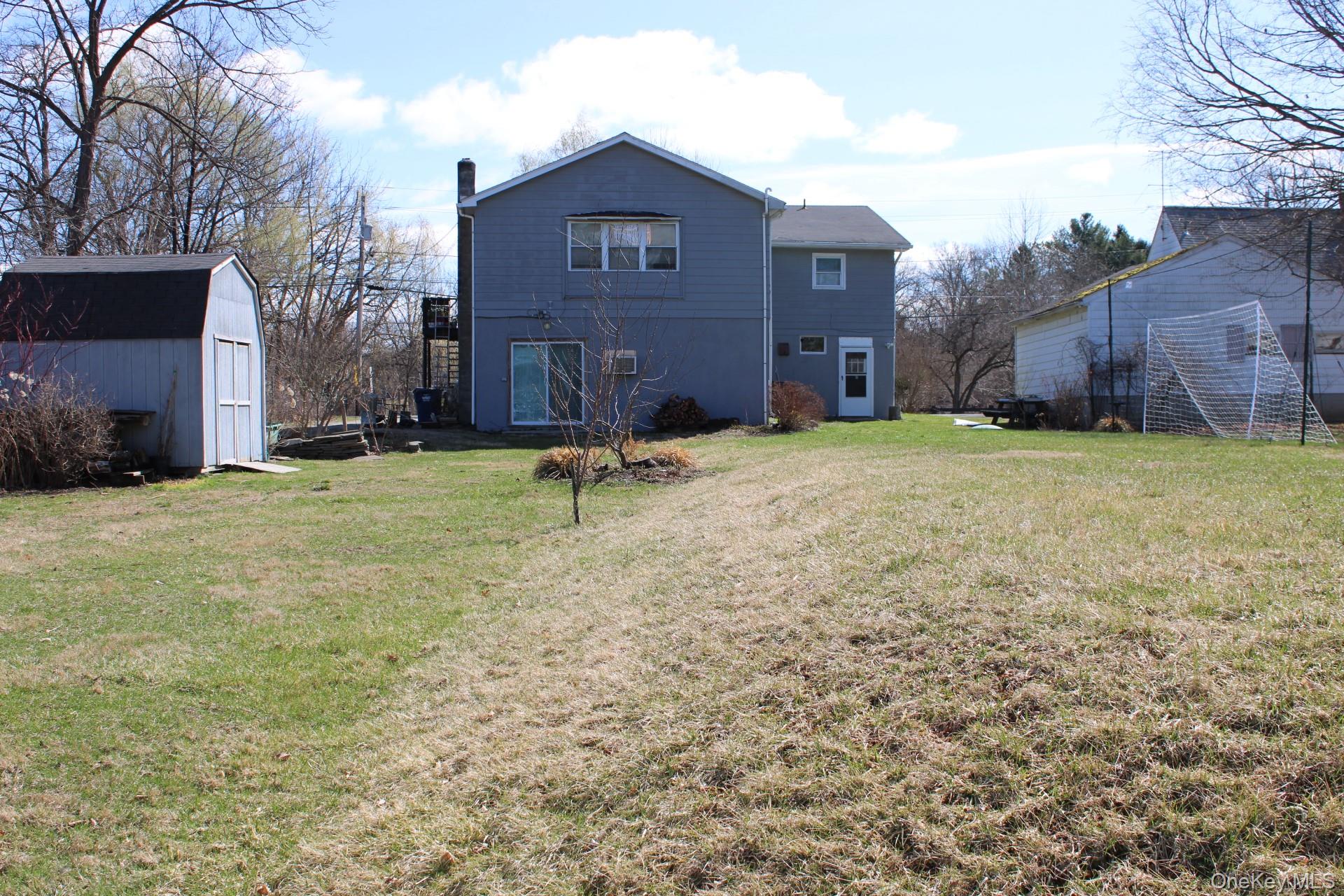 Rear view of house featuring a shed, an outbuilding, and a yard