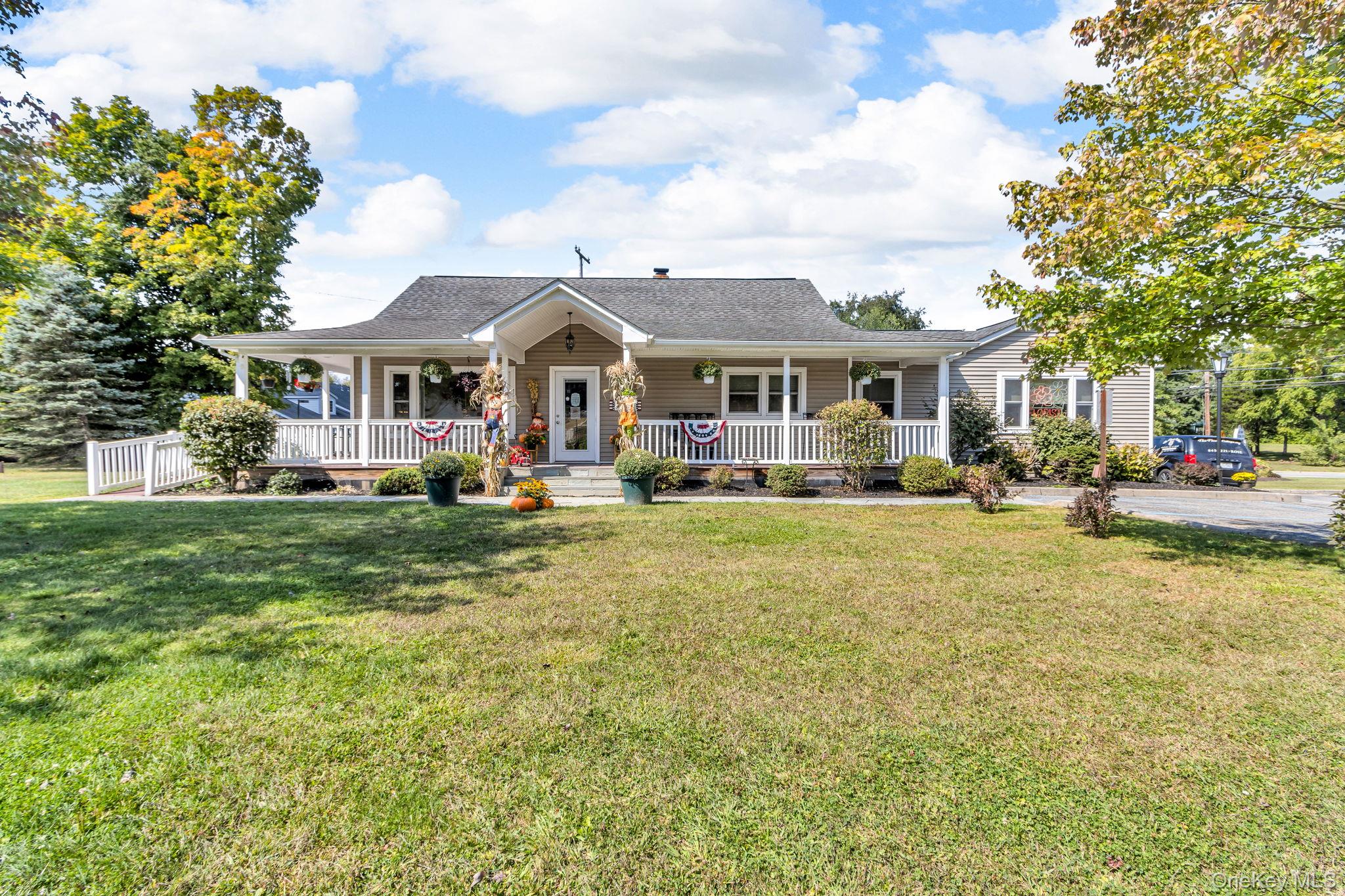 View of front of property featuring a porch, a front yard, and roof with shingles