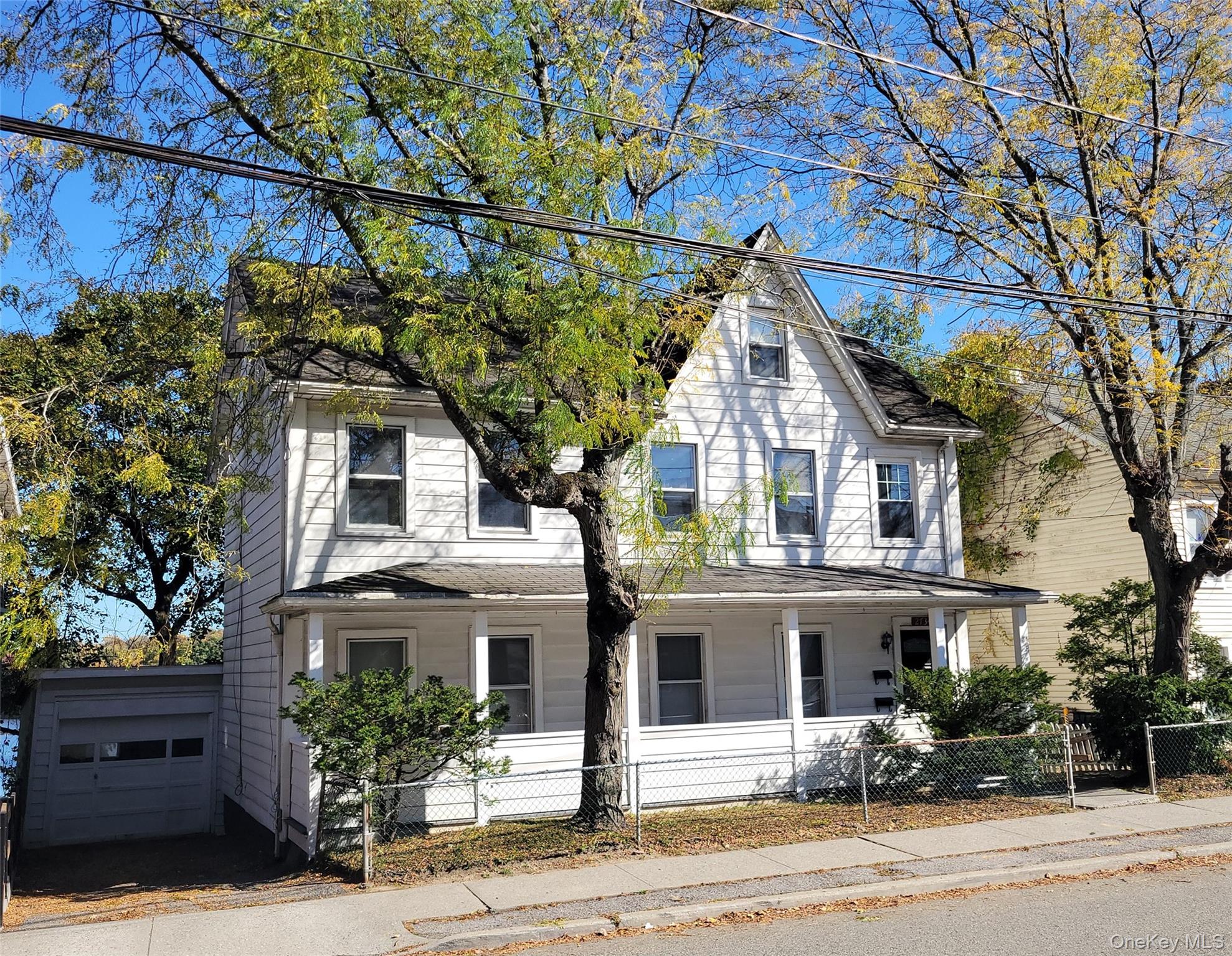 View of front of house with covered porch, a fenced front yard, and garage