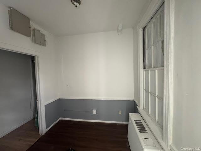 Unfurnished dining area featuring dark wood-style flooring and an AC wall unit