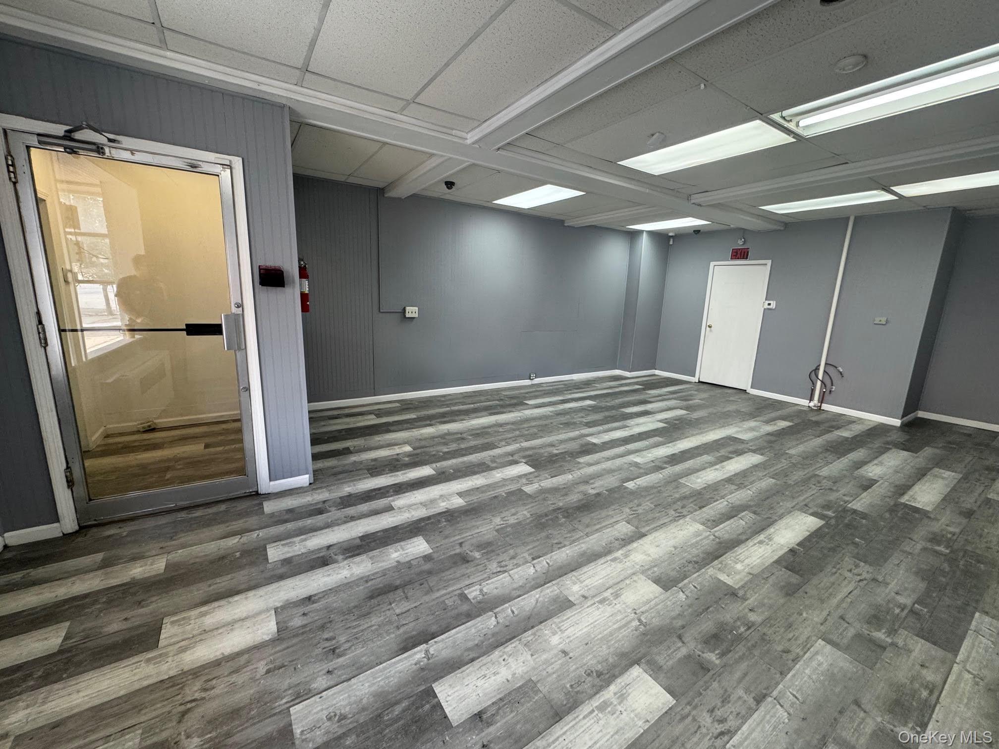 Unfurnished room featuring wood finished floors and a drop ceiling