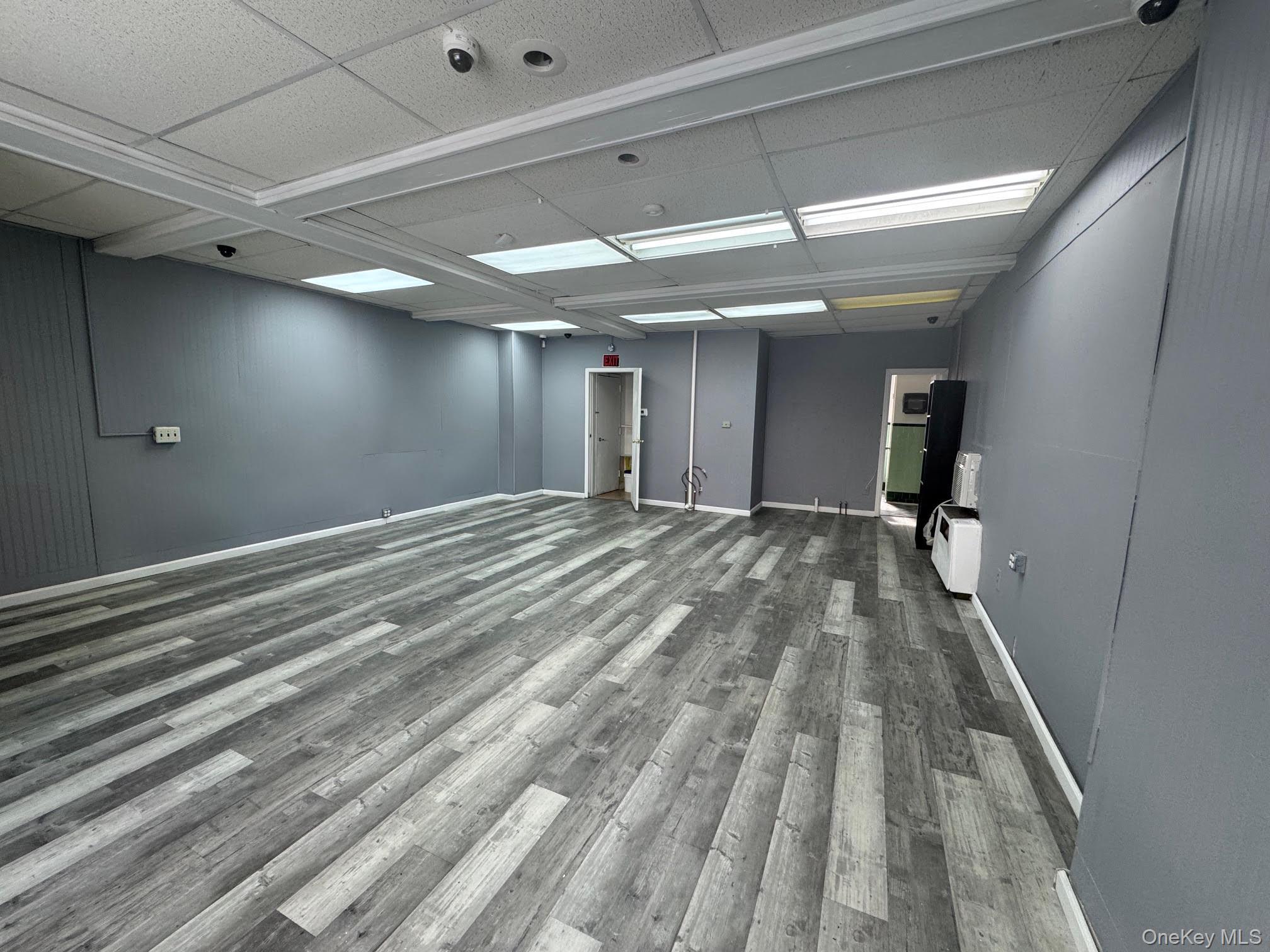 Spare room featuring a drop ceiling and dark wood-type flooring