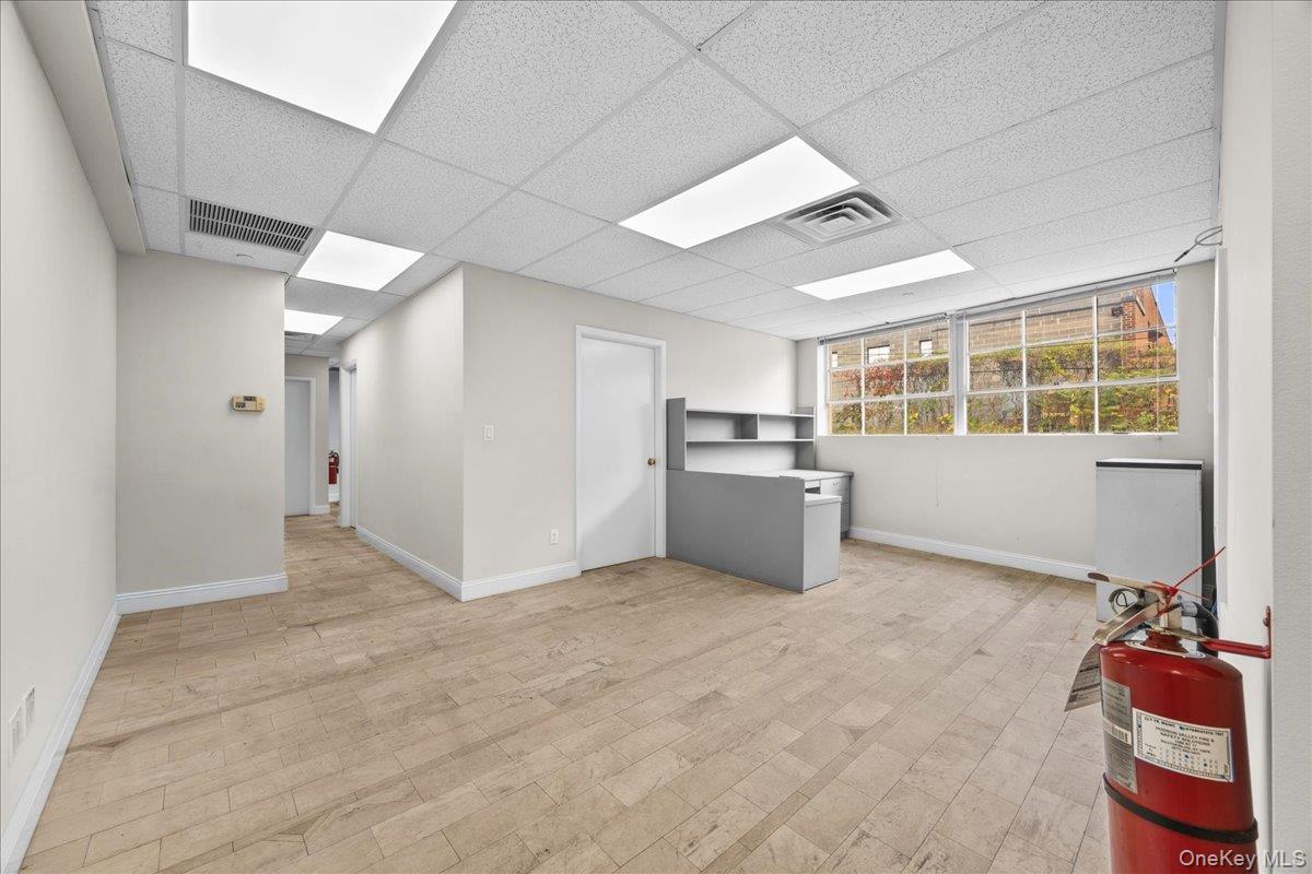 Below grade area with light wood finished floors and a drop ceiling