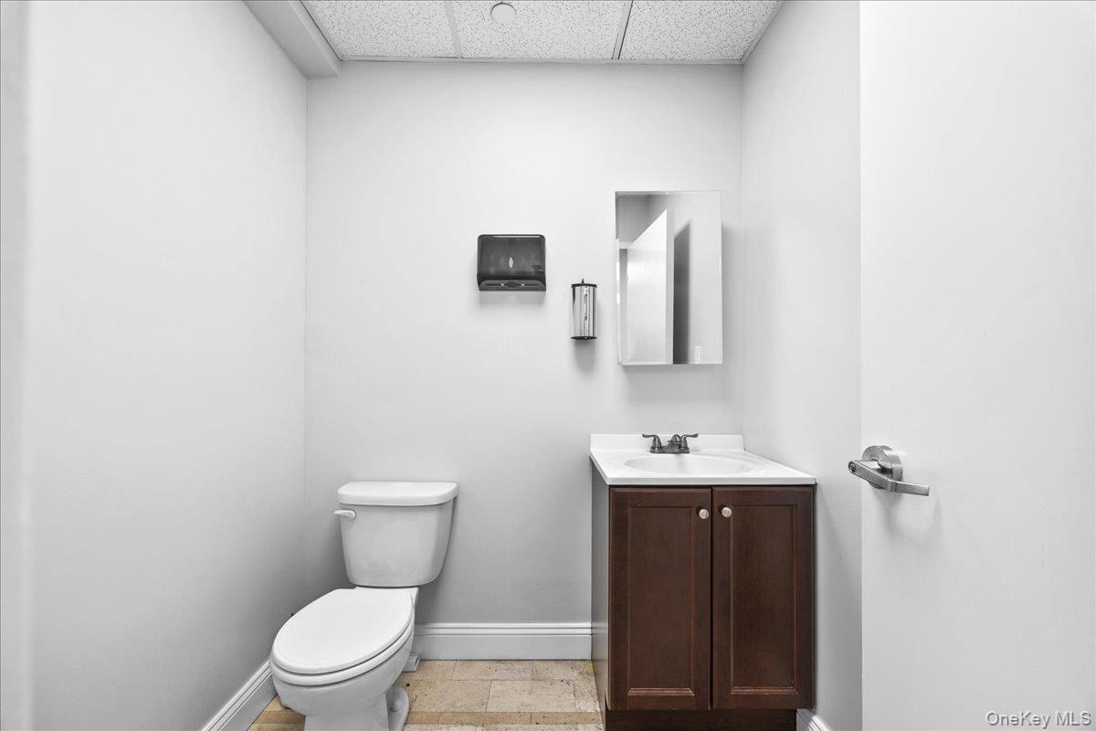 Bathroom with a drop ceiling, vanity, and light tile patterned floors