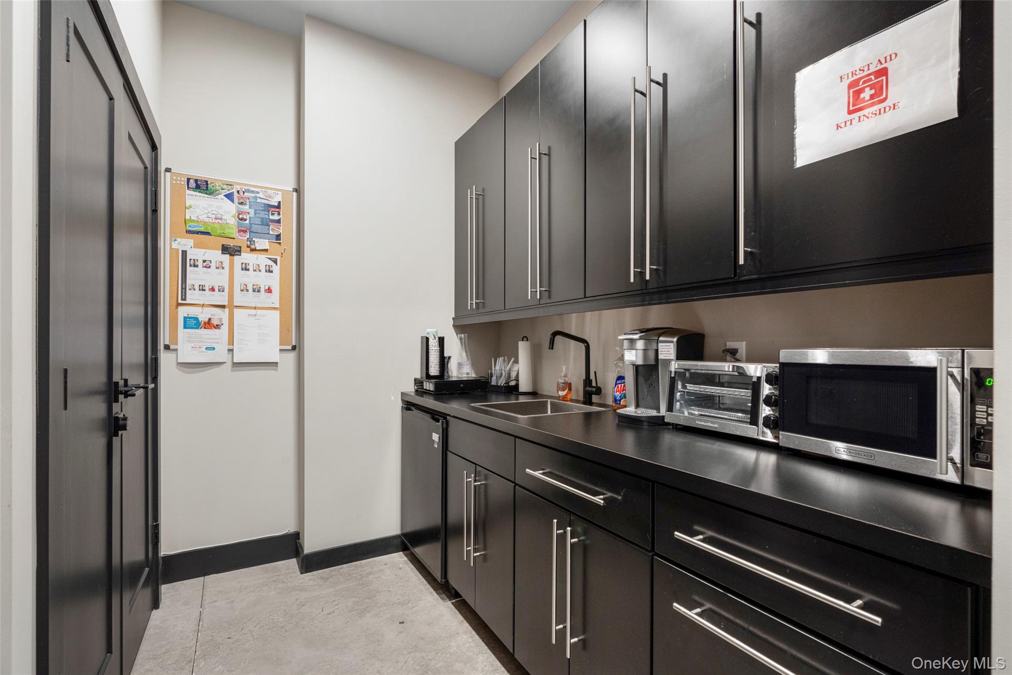 Kitchen with dark cabinetry, stainless steel microwave, dark countertops, and dishwashing machine
