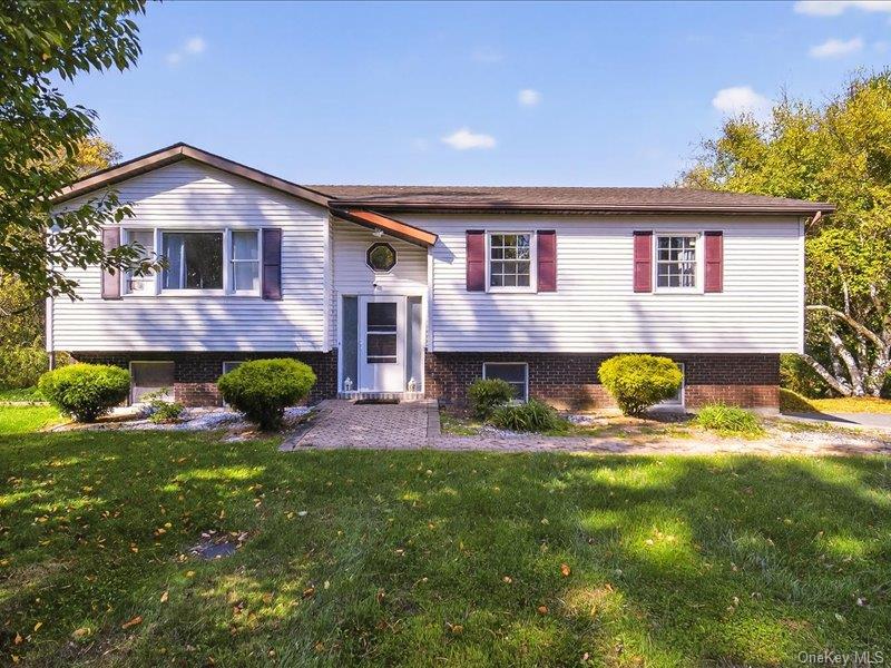 Split foyer home with a front lawn and brick siding