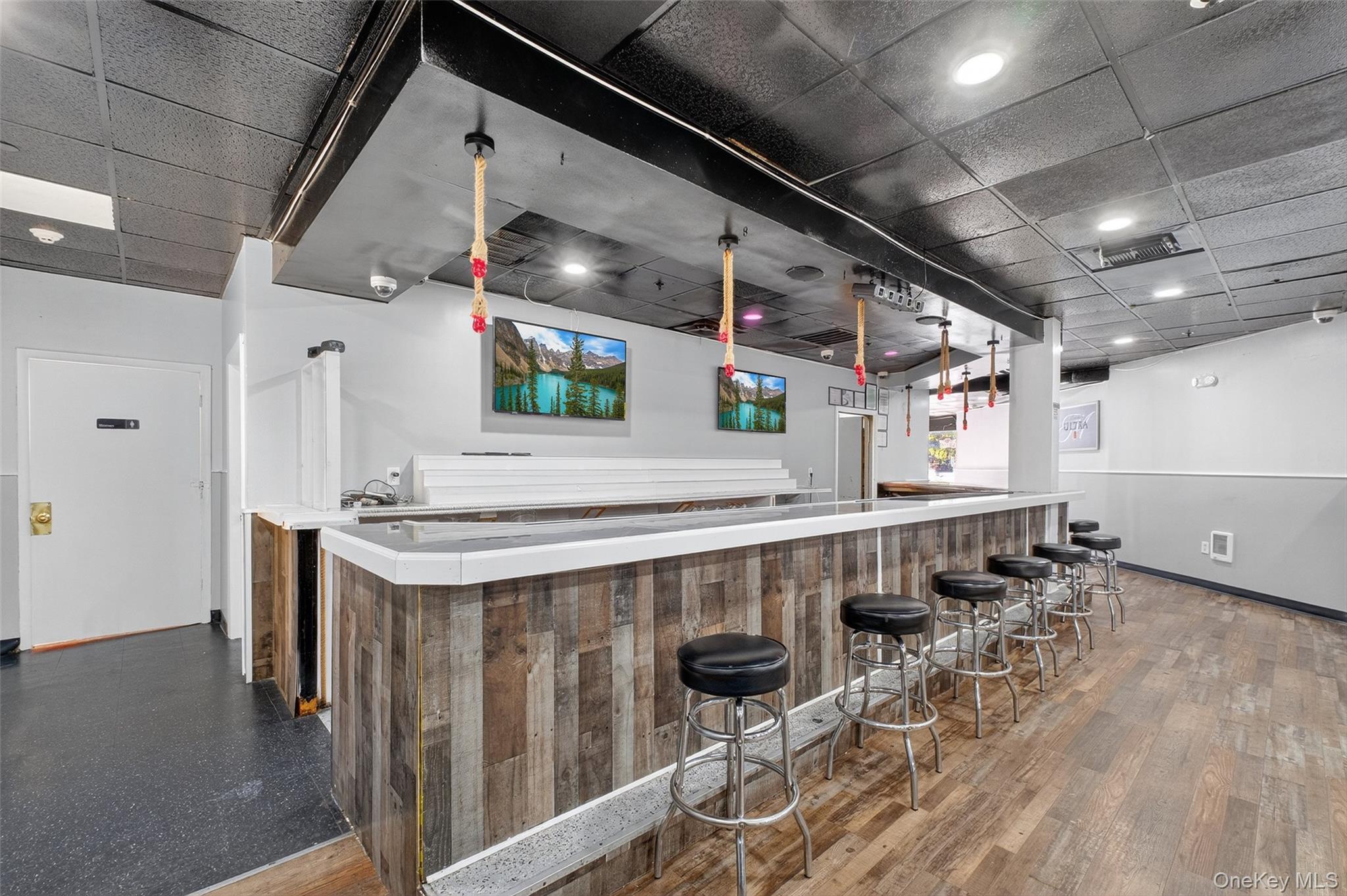 Indoor wet bar featuring a paneled ceiling and light countertops