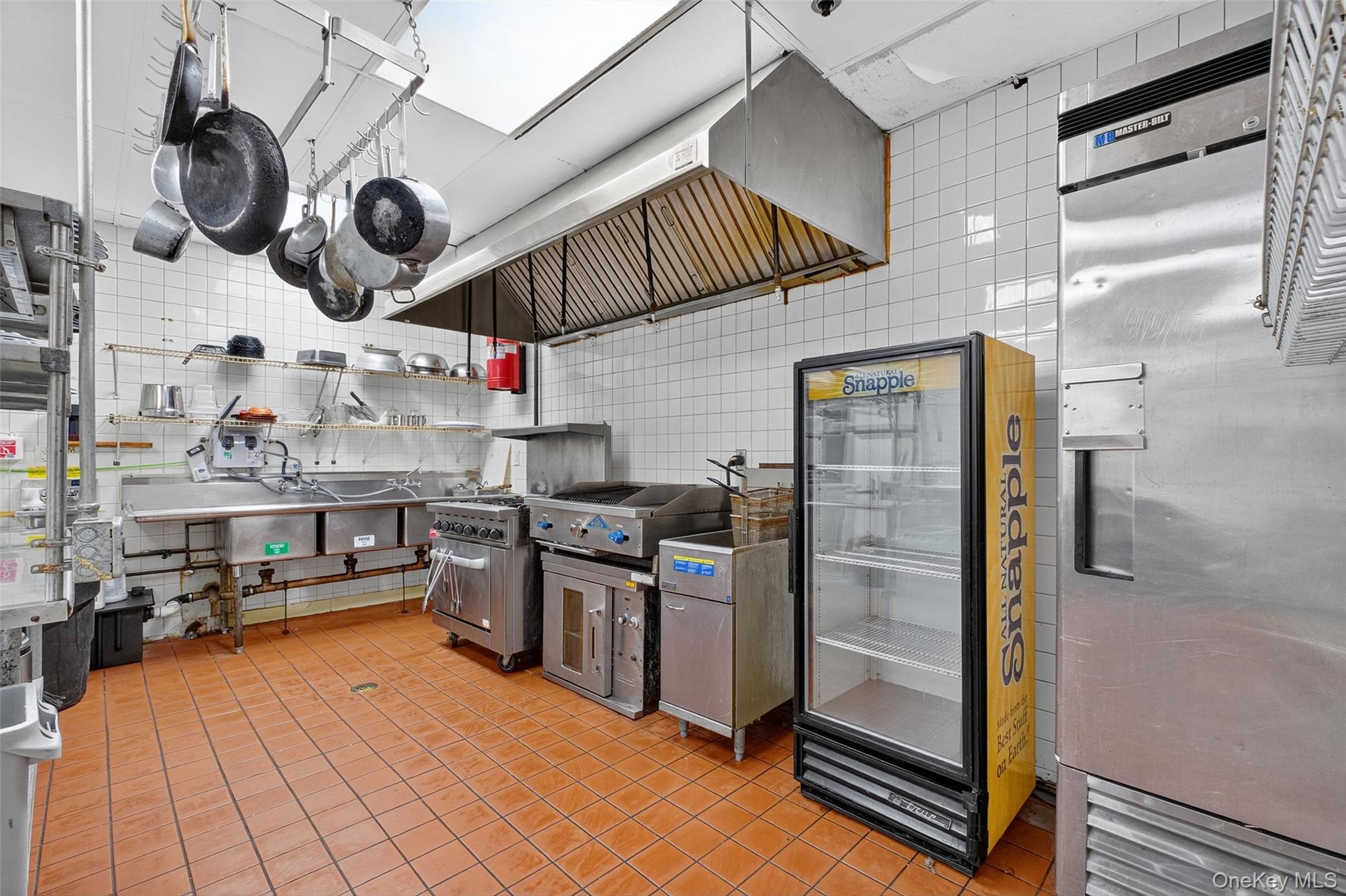 Kitchen featuring freestanding refrigerator, ventilation hood, and open shelves
