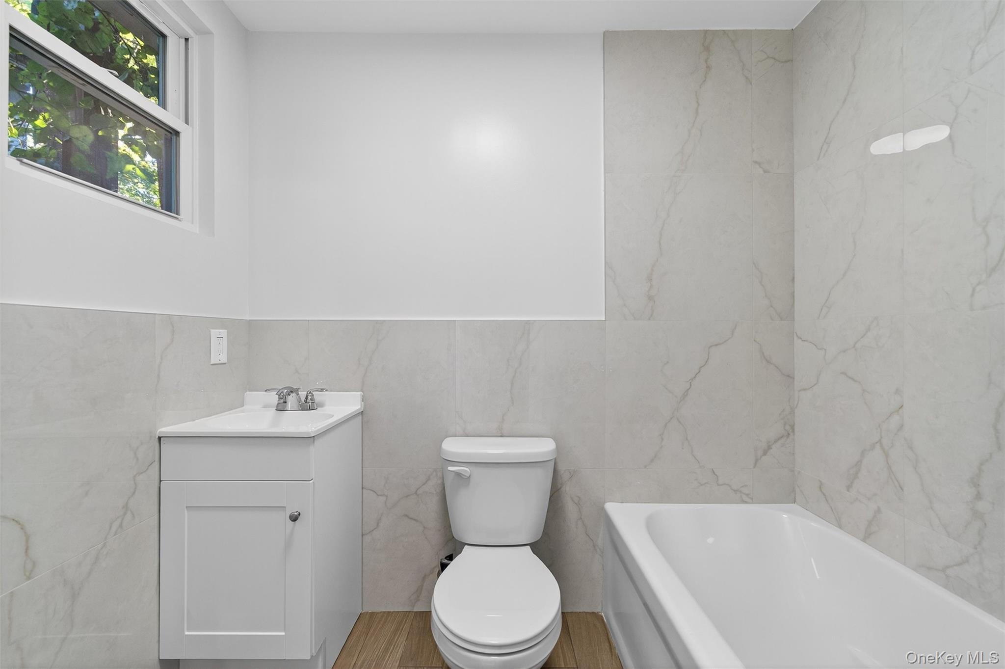 Bathroom featuring tile walls, vanity, and a tub