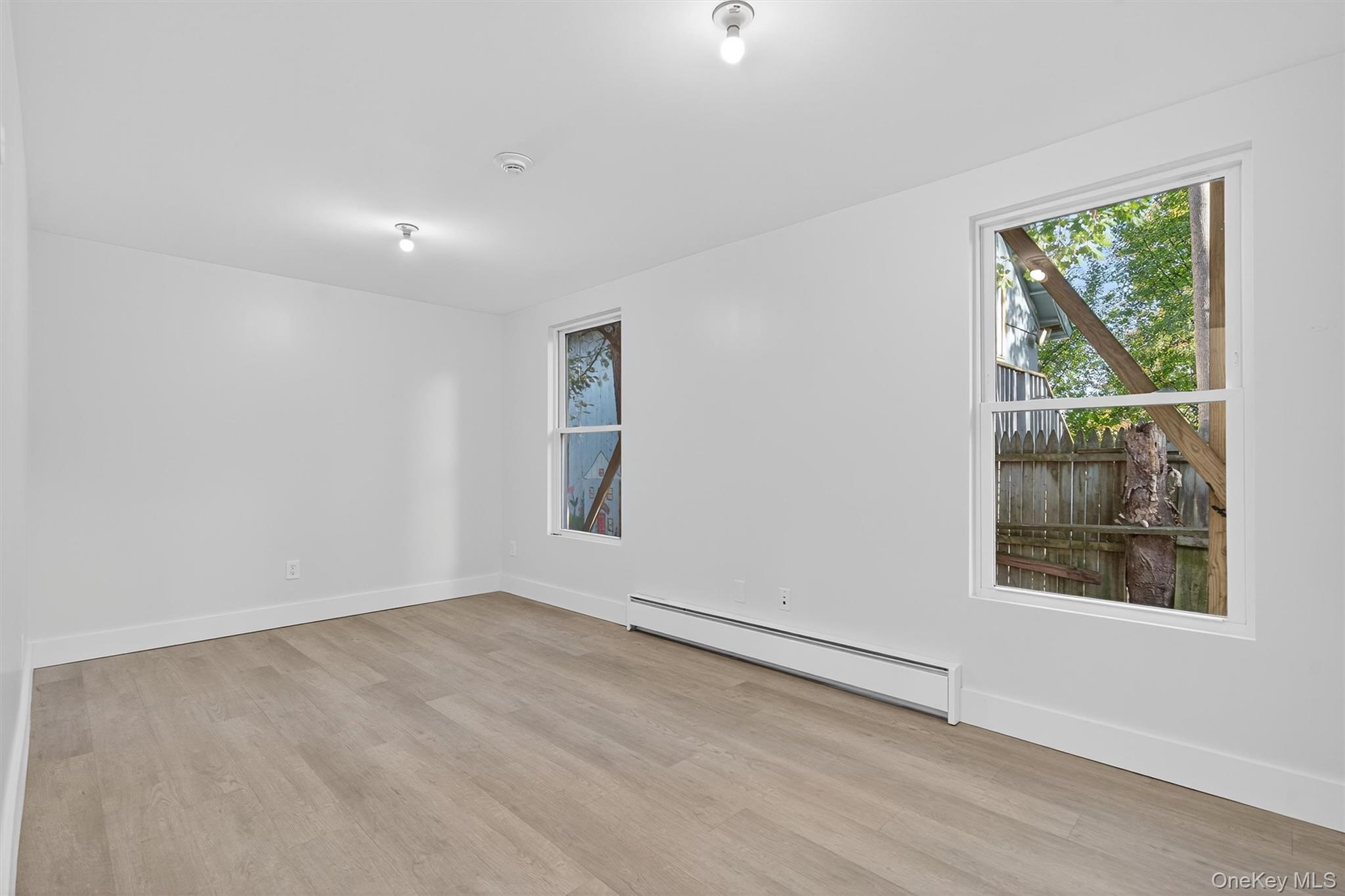 Spare room featuring a baseboard radiator and light wood-style floors