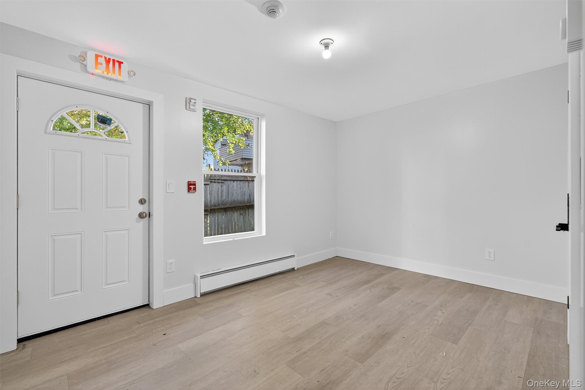Entrance foyer with baseboard heating, healthy amount of natural light, and light wood-style floors