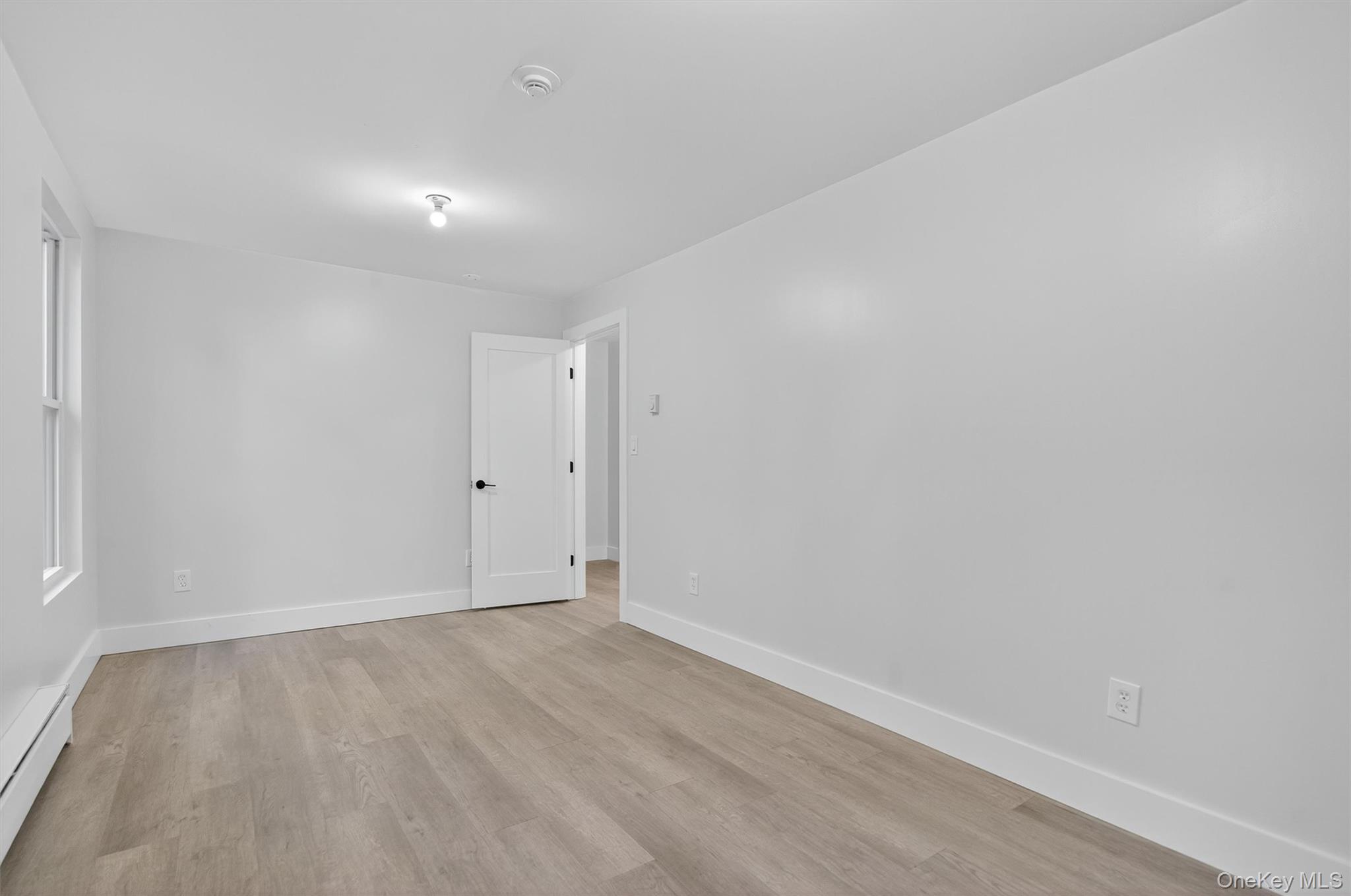 Unfurnished room with light wood-type flooring and a baseboard heating unit