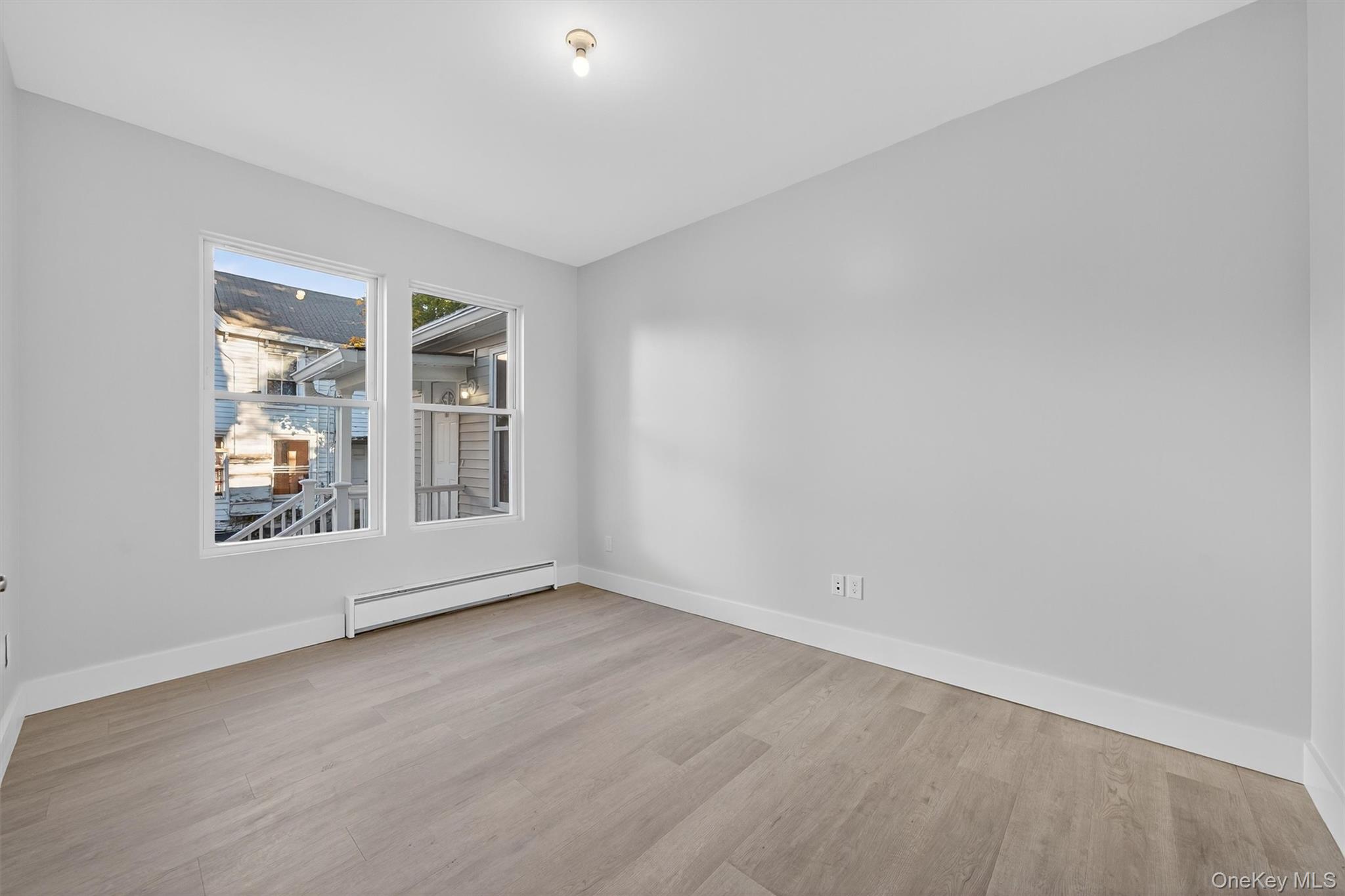 Unfurnished room featuring baseboard heating and light wood-style flooring