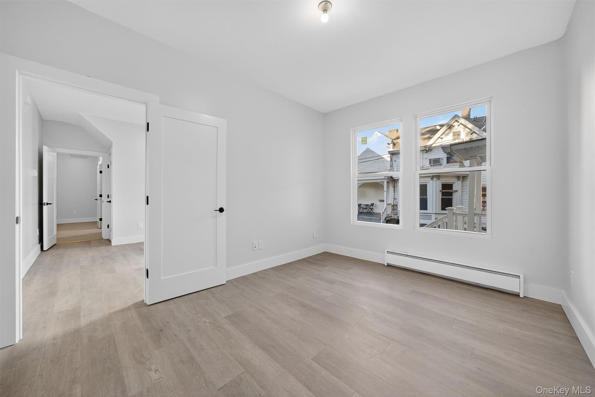 Unfurnished room featuring a baseboard radiator and light wood-type flooring