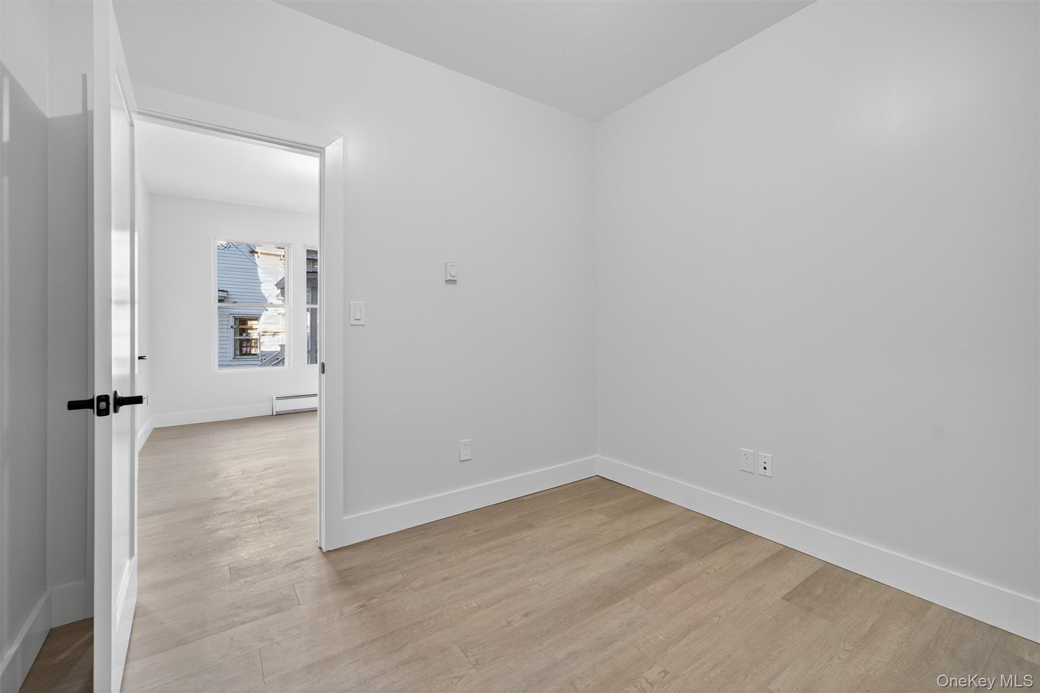 Empty room with light wood finished floors and a baseboard radiator