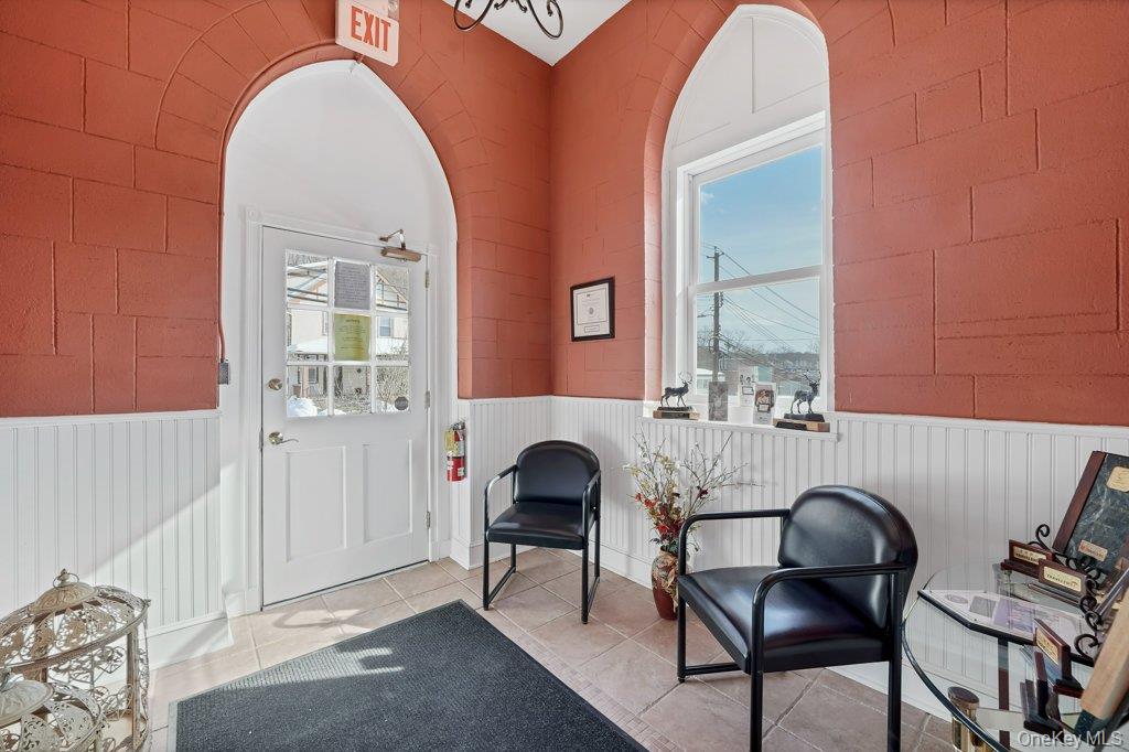 Doorway with plenty of natural light, tile patterned flooring, and a wainscoted wall