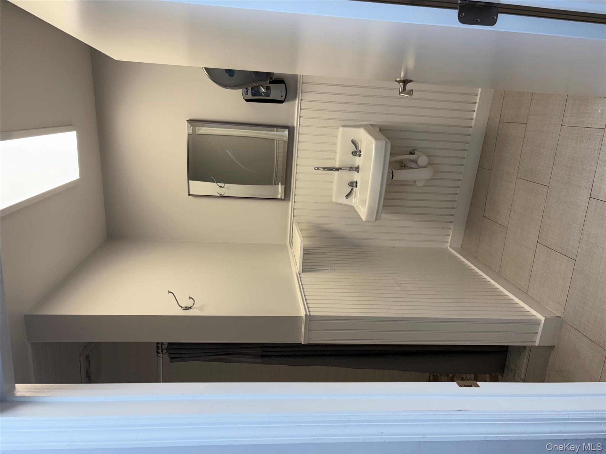 Full bath with a shower with shower curtain, a wainscoted wall, and light tile patterned floors