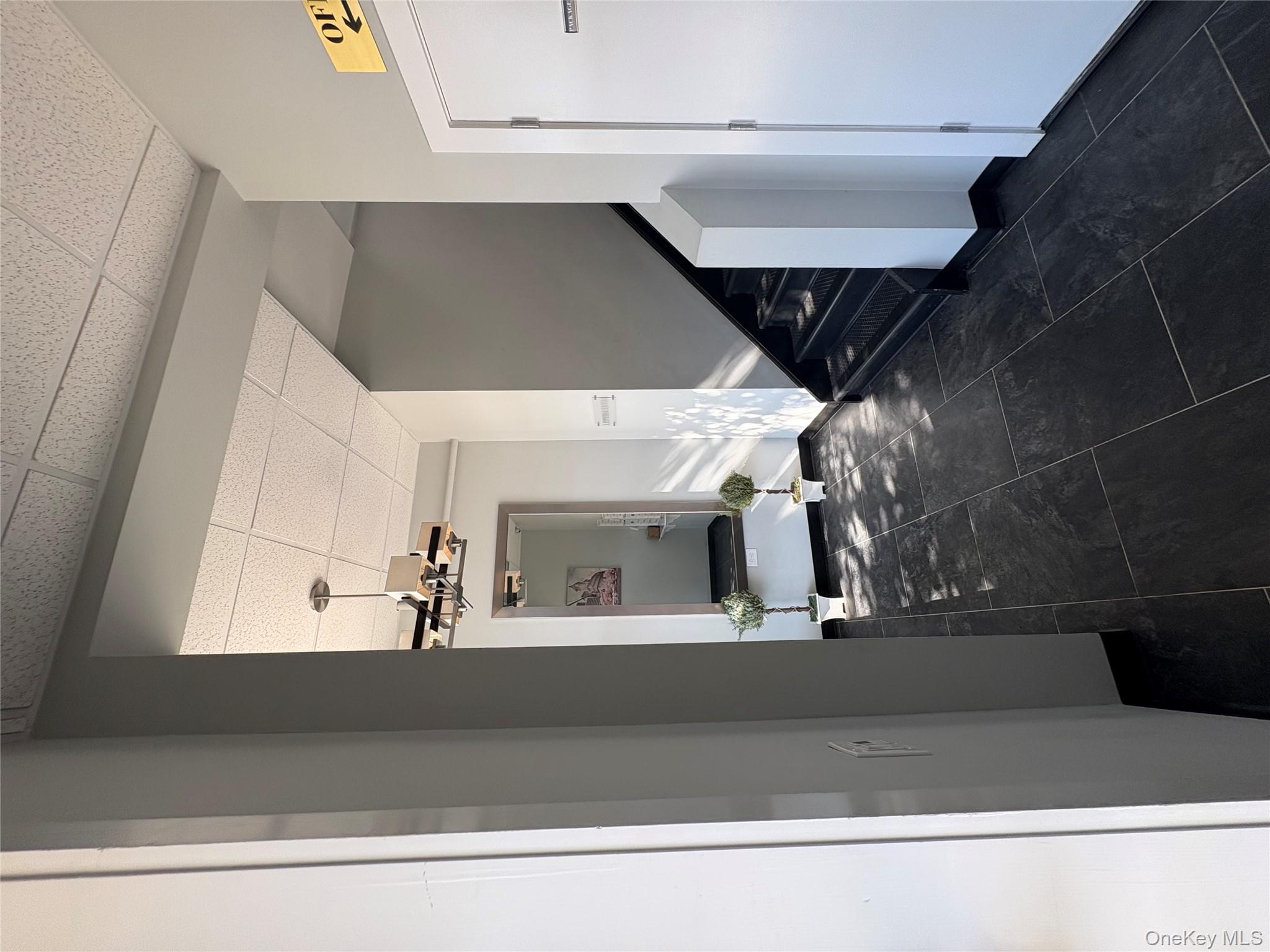 Hall featuring a paneled ceiling, stairway, and a chandelier