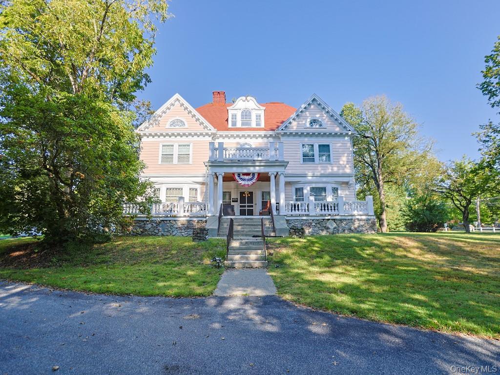 View of front of property featuring a porch, a chimney, and a front lawn