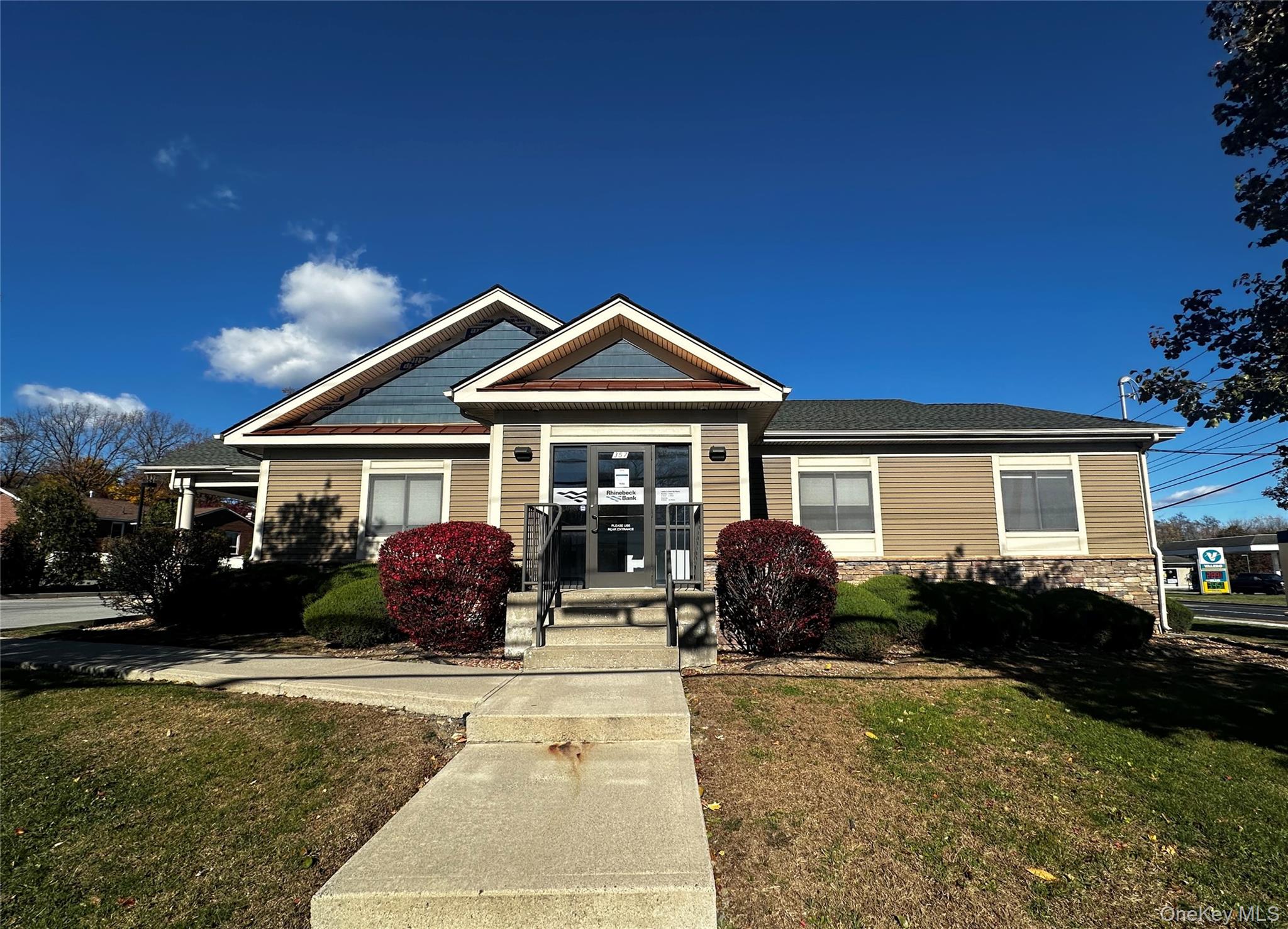 View of front of house with a front yard, stone siding, and a shingled roof