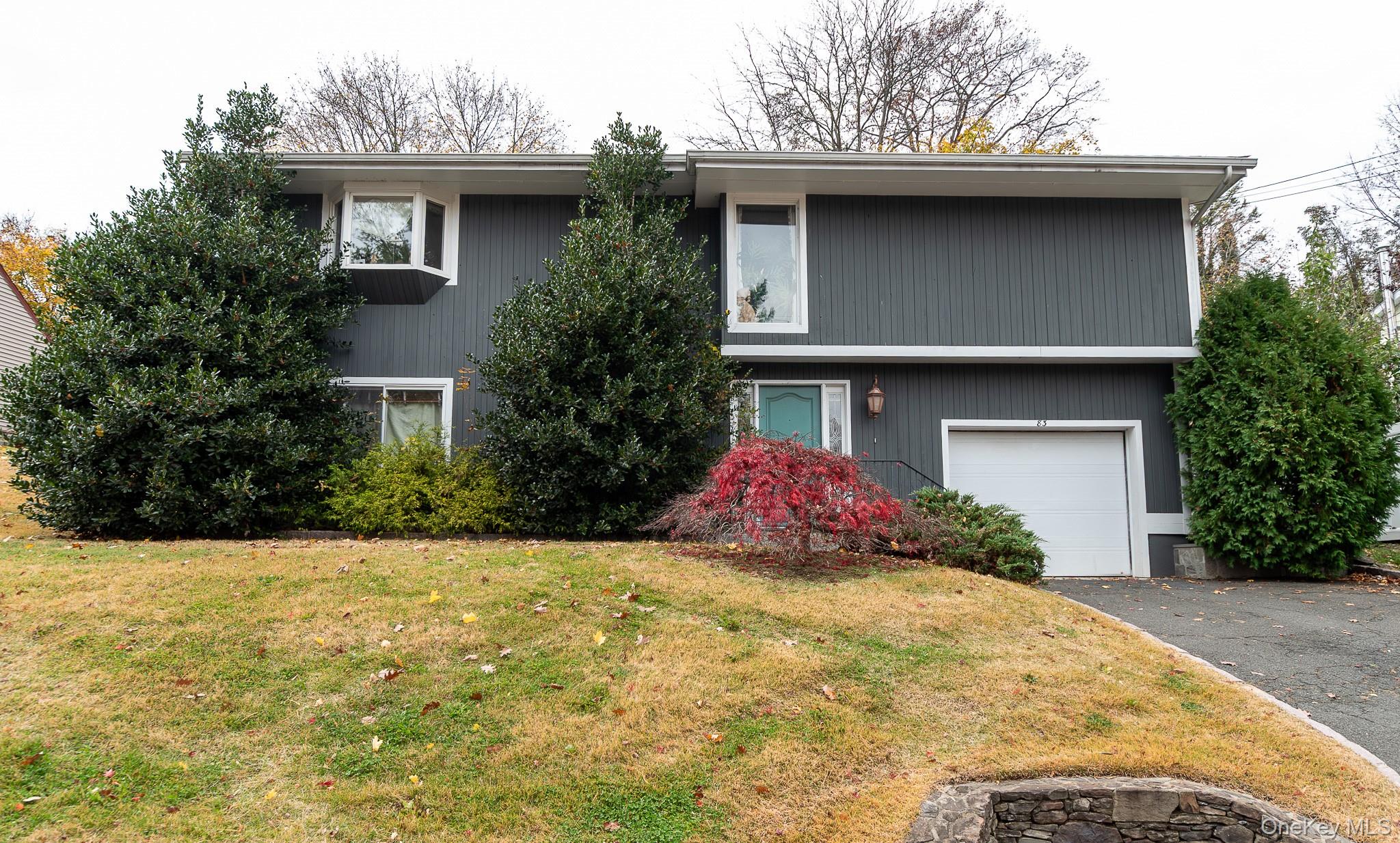 View of front of property with an attached garage, a front lawn, and driveway